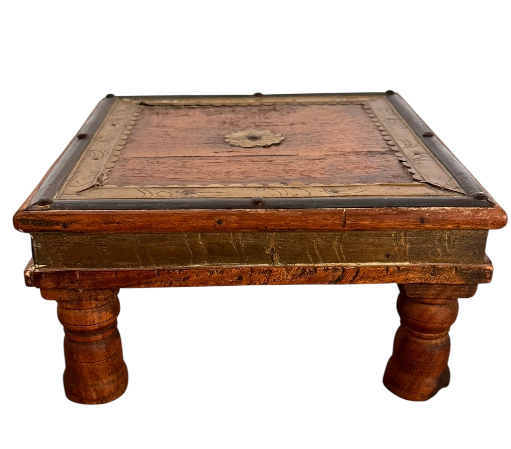 Stack of three vintage Indian teak bajot nesting tables featuring brass-clad edges, repoussé details, and short turned legs against a white background.