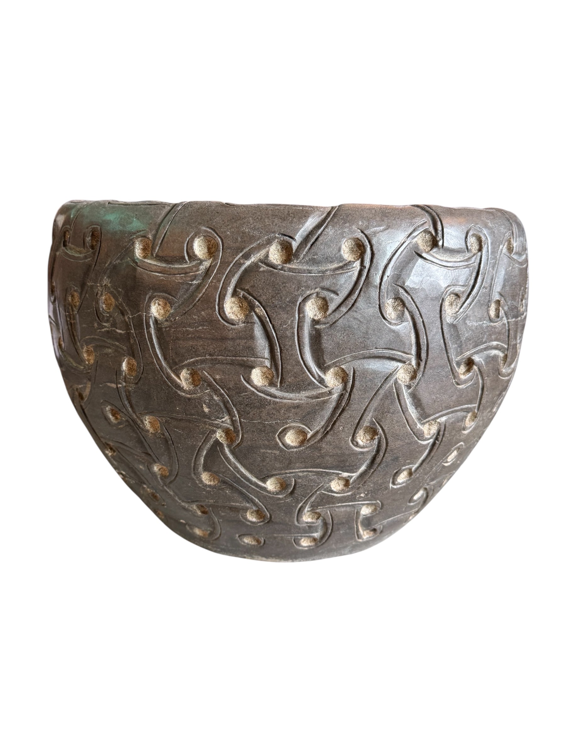 A heavy stone planter, featuring an intricate, hand-carved pattern resembling Celtic knot work.