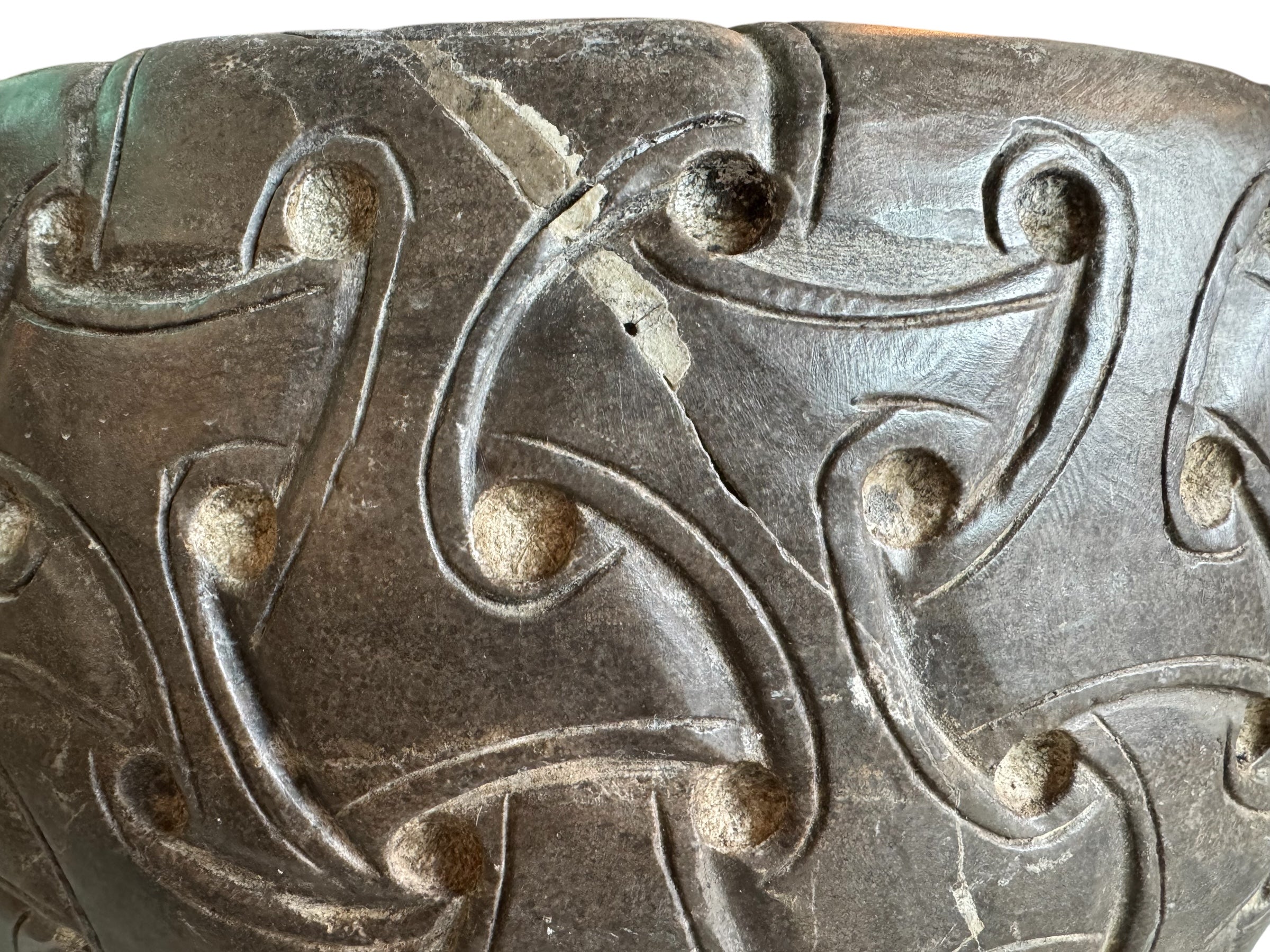 A heavy stone planter, featuring an intricate, hand-carved pattern resembling Celtic knot work.