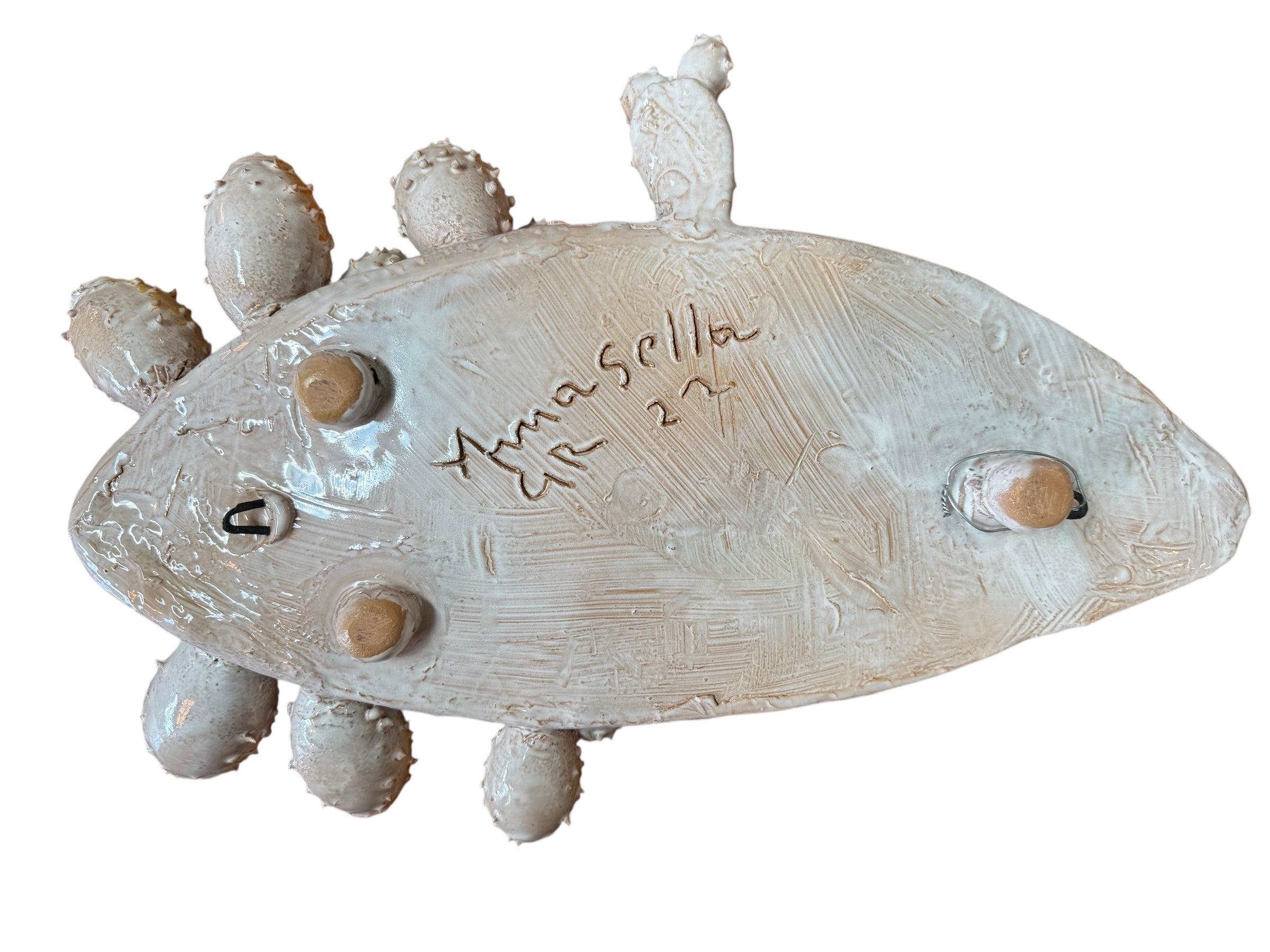 A white and orange, glazed ceramic platter in the shape of a prickly pear cactus pad with attached prickly pear fruit. The surface has raised dots representing spines.