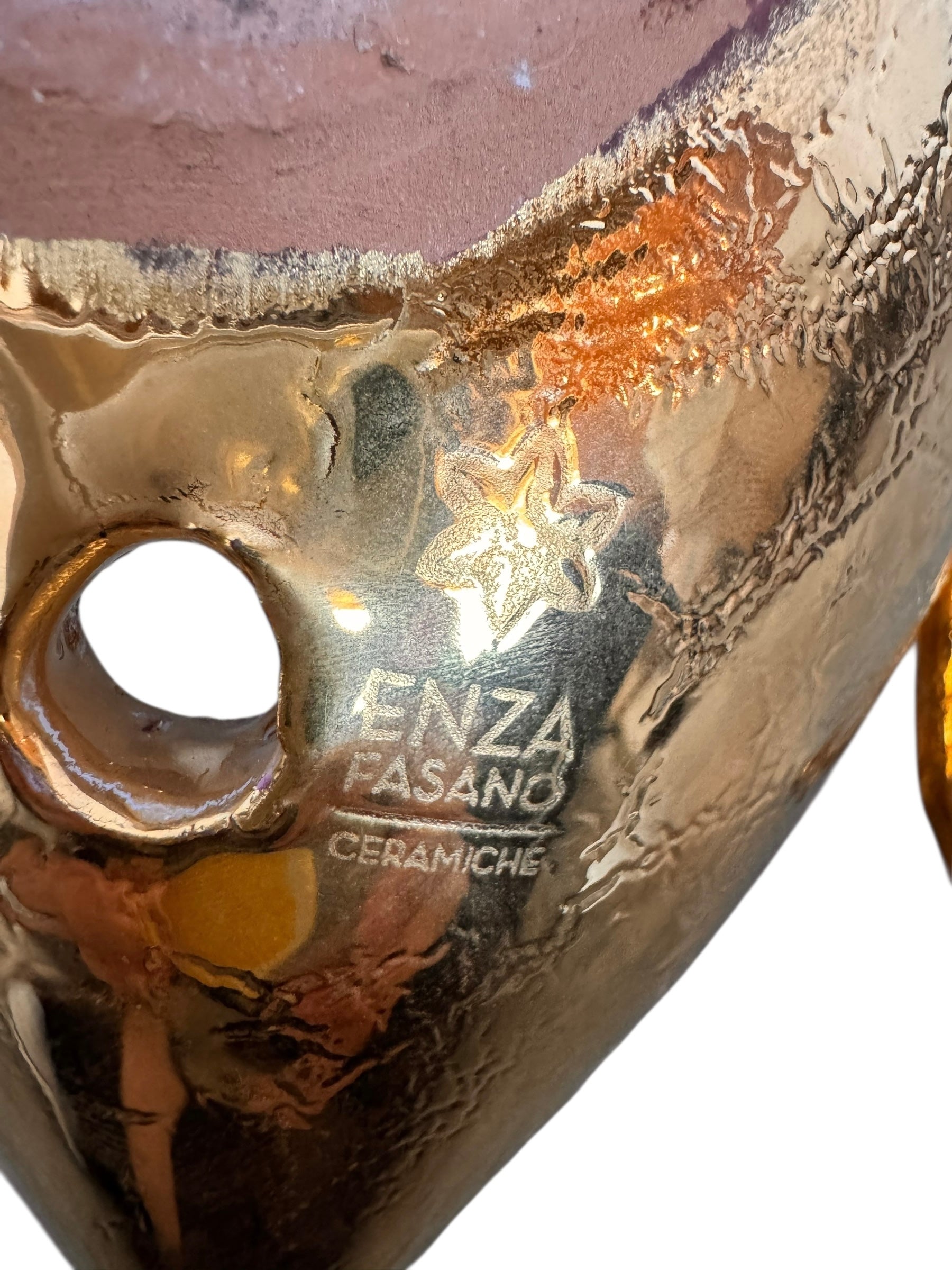 A handcrafted ceramic sculpture of a rhinoceros beetle by Enza Fasano, featuring a brilliant, high-gloss gold metallic finish. The beetle is captured in a dynamic, slightly upturned pose with detailed textures on its ribbed shell and prominent, curved horns. The piece reflects light across its polished surface, showcasing the artist’s signature fusion of traditional Pugliese pottery and contemporary luxury.