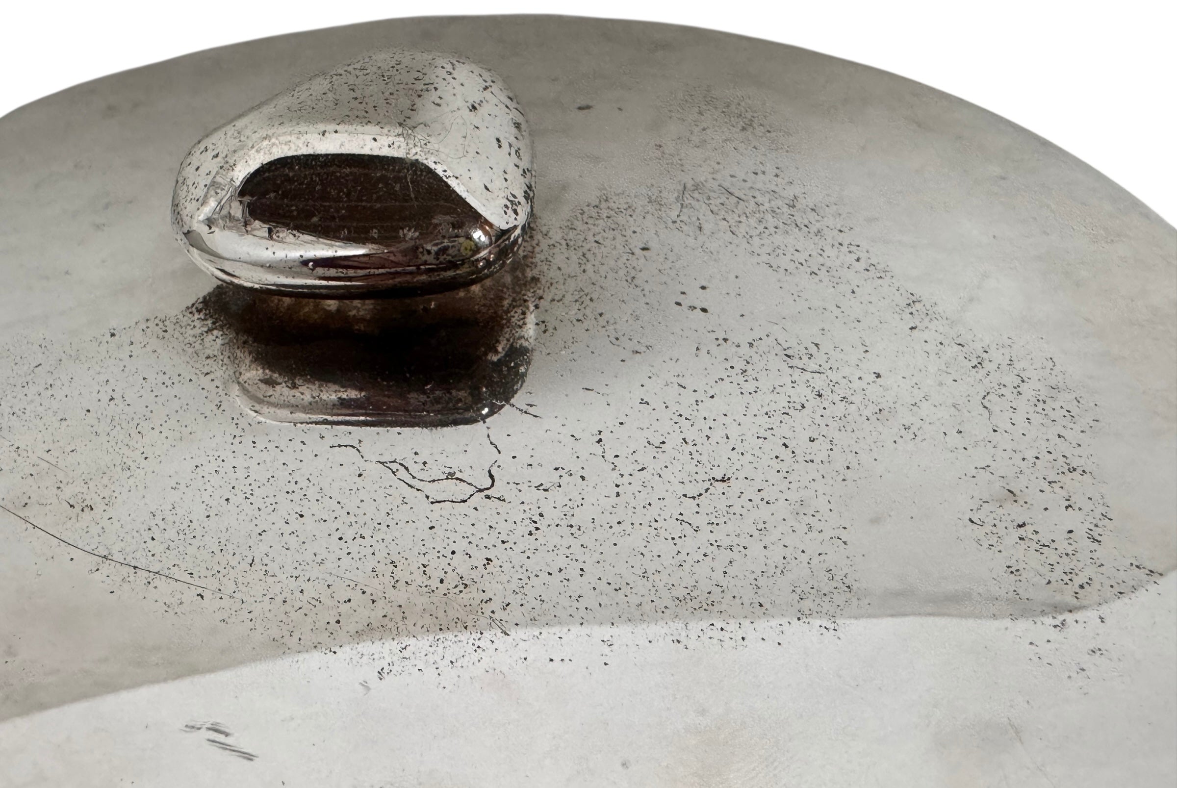 Round St. James silver-plated lidded serving dish from the 1980s, featuring a minimalist modernist design with geometric side handles and a sculptural, biomorphic finial, showing visible vintage wear and pitting on the metallic surface.