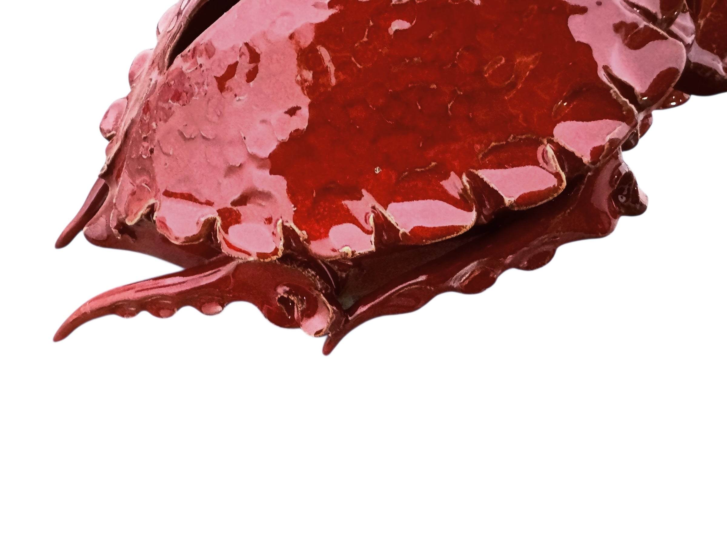 A handcrafted ceramic sculpture of a rhinoceros beetle by Enza Fasano, featuring a vibrant, glossy deep-red glaze. The piece is stylized with smooth, rounded contours and prominent, elegant horns extending forward. Its surface reflects light, highlighting the rich texture and artisanal detail of the clay.