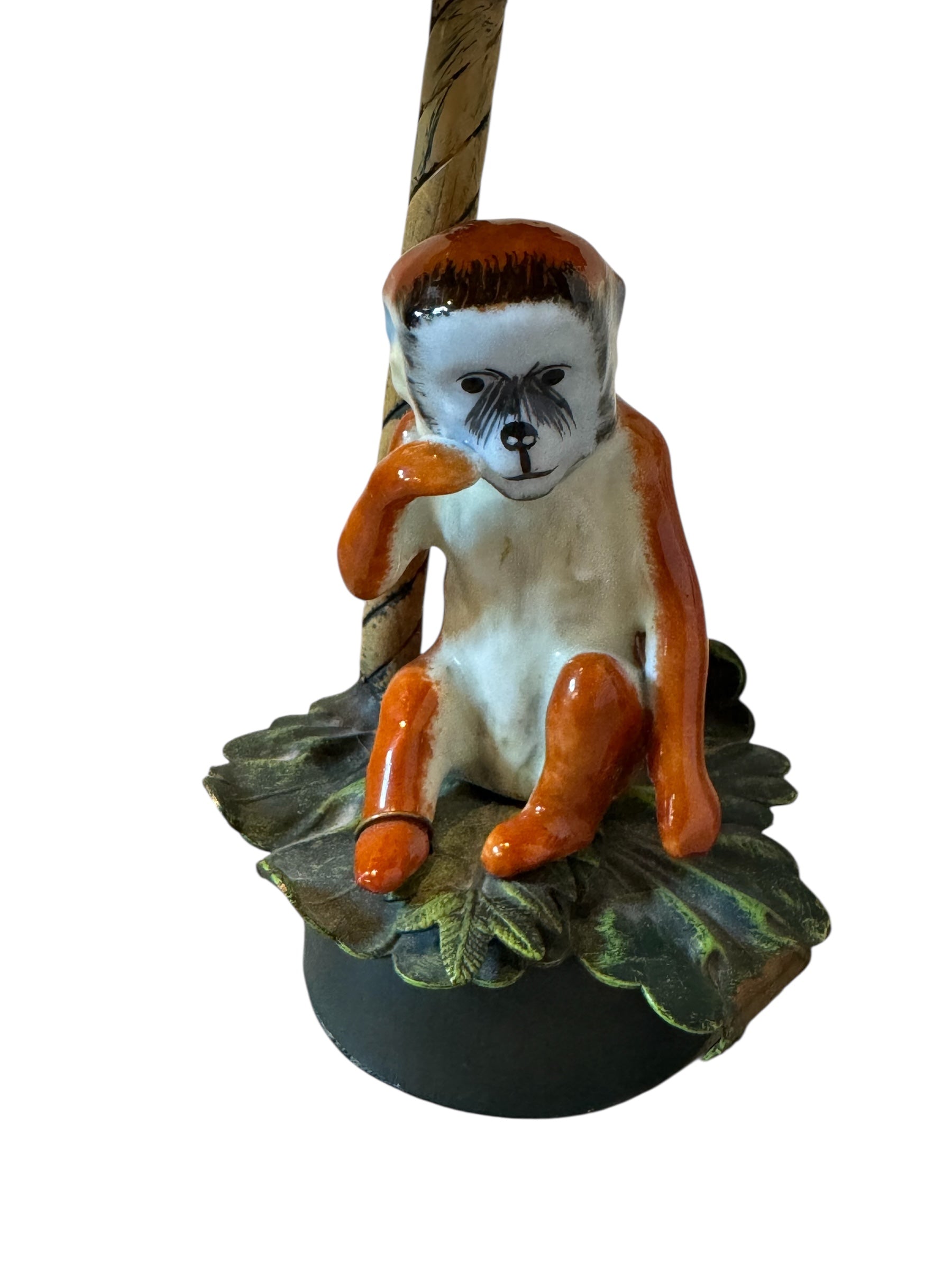 Monkey figurine with a leaf and branch on a white background