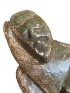 Figural sculpture in the Shona style, Zimbabwe. Two abstracted figures are intertwined, carved from greenish-brown soapstone. Sculpture rests on a dark iron stand.