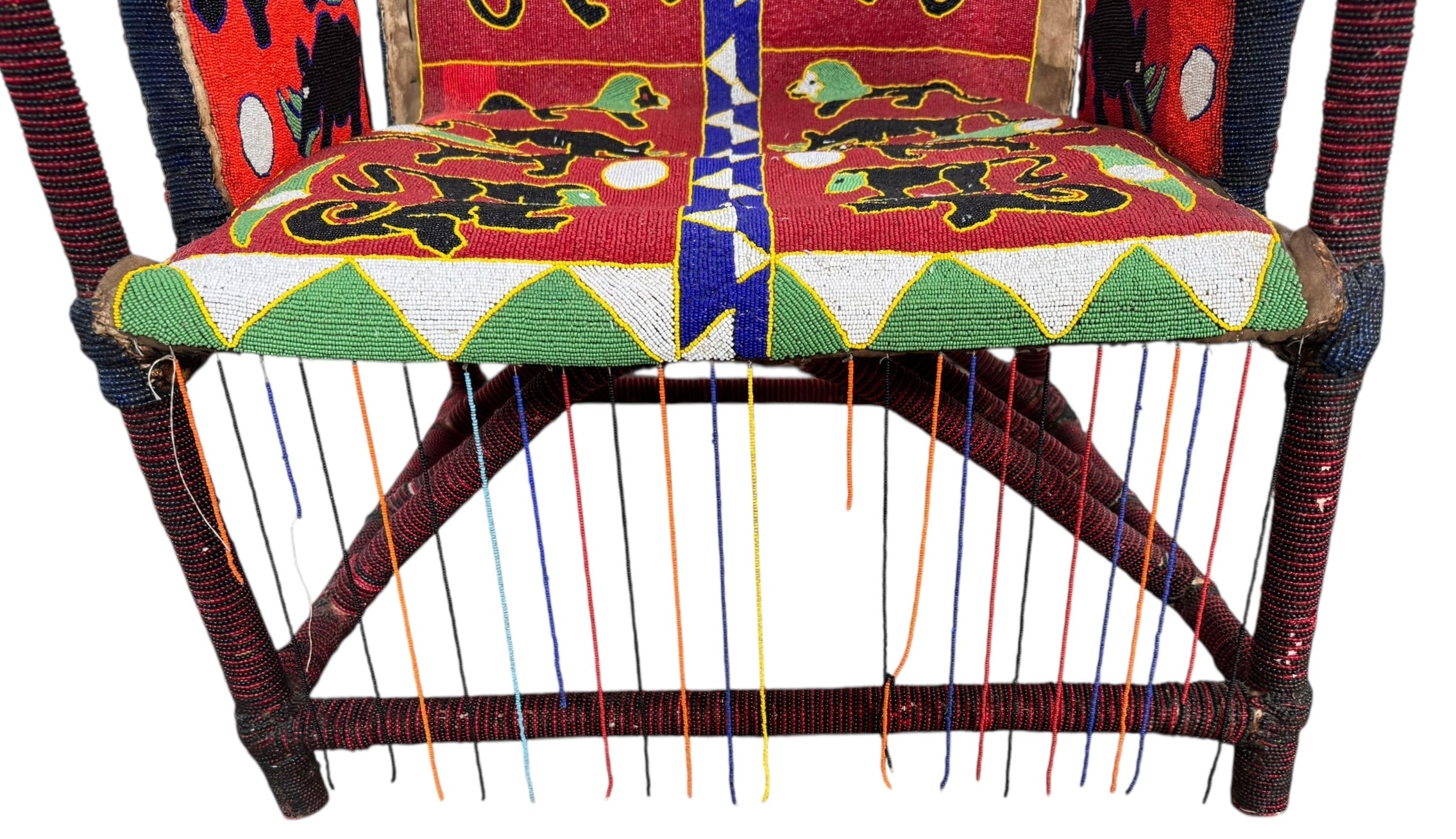 Close-up of a Yoruba beaded armchair, featuring vibrant red, blue, and green beads in a pattern of stylized masks and animals such as lions and zebras