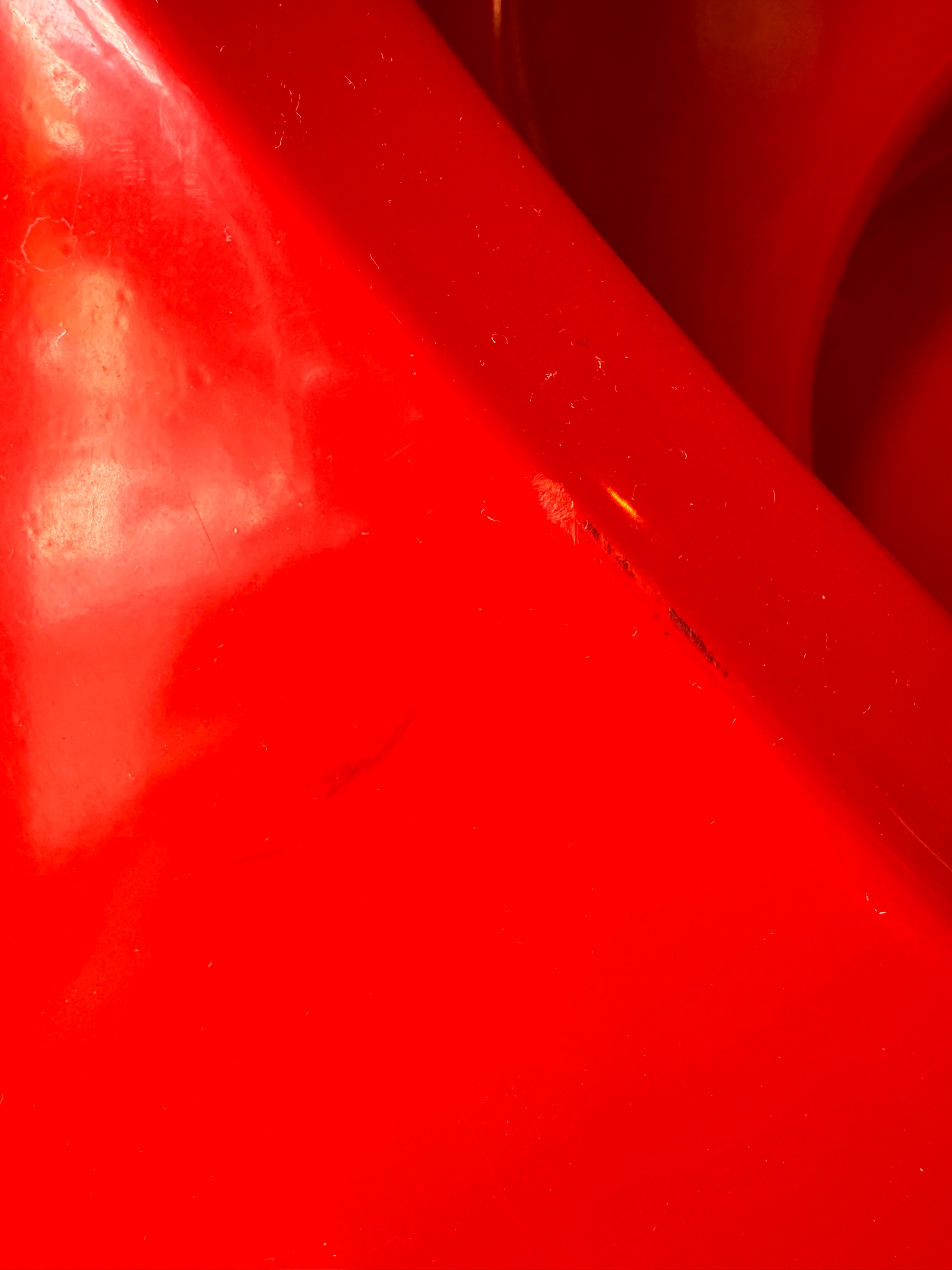 A top-down, straight-on view of a vintage, high-gloss cherry red bathtub. The tub basin is molded into a distinct double-tiered heart shape, with a shallower outer heart cascading into a deeper, smaller inner heart basin centered within a wide rectangular red deck.