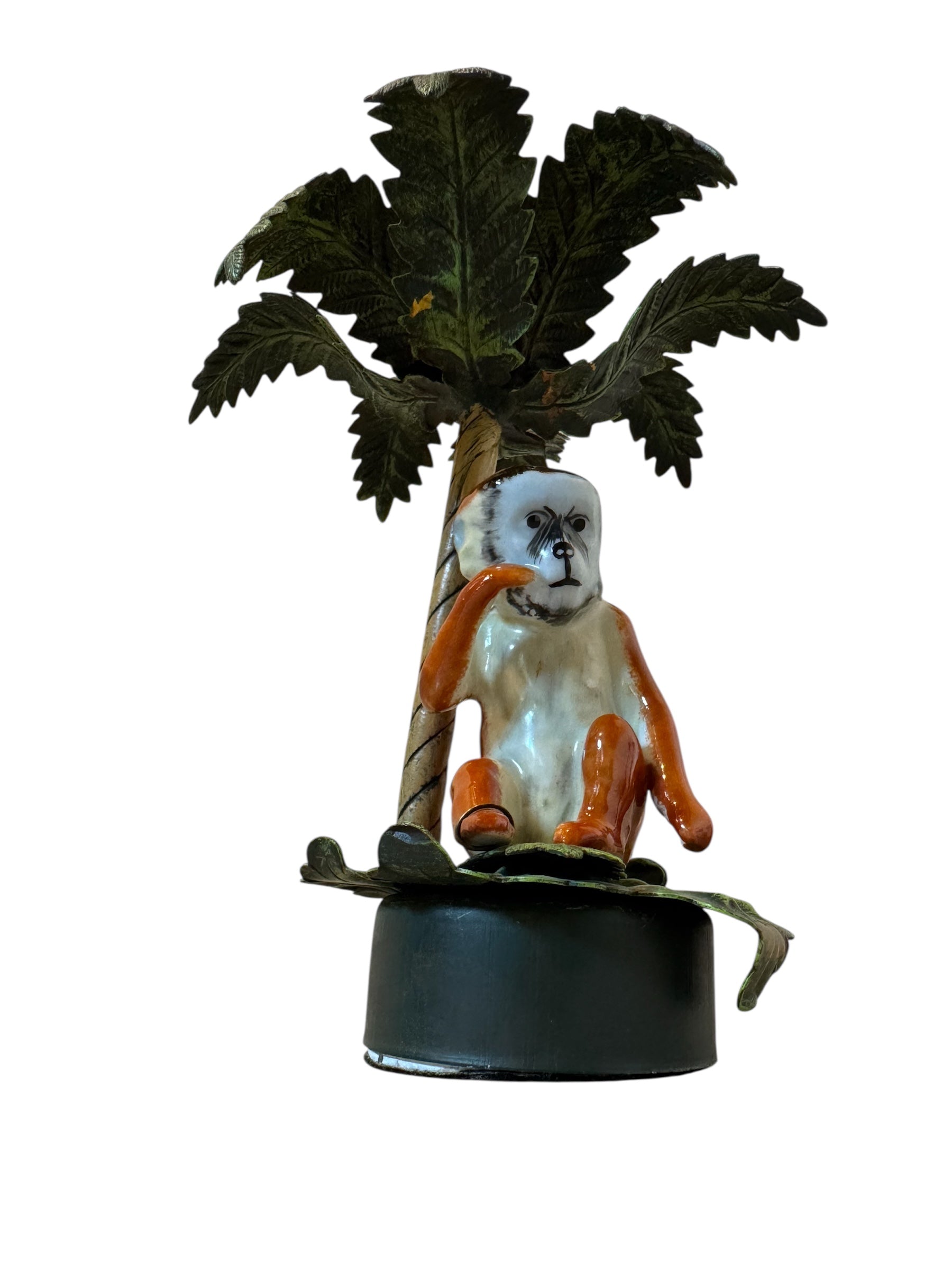 Decorative figurine of a monkey sitting under a palm tree on a white background