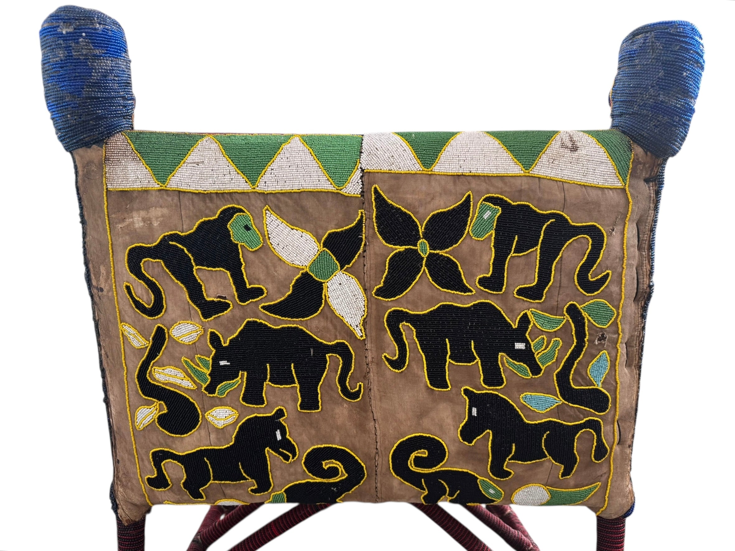 Close-up of a Yoruba beaded armchair, featuring vibrant red, blue, and green beads in a pattern of stylized masks and animals such as lions and zebras