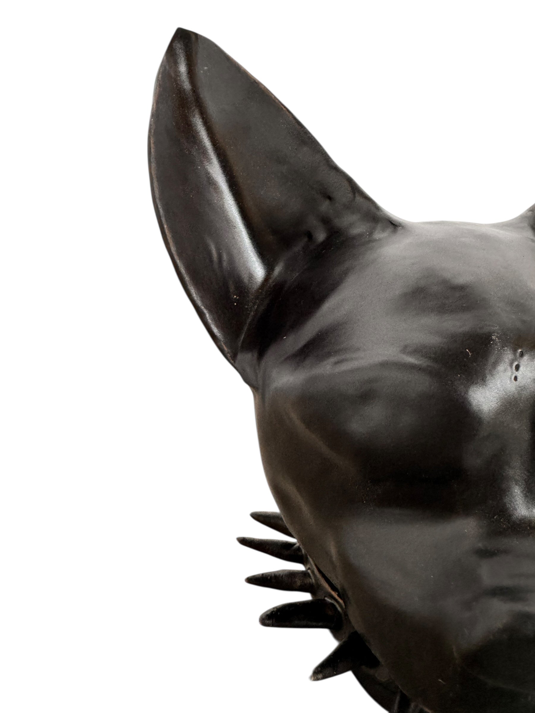 A smooth, dark black-colored ceramic sculpture of a Miniature Pinscher's head. The stylized dog features large, upright pointed ears and a prominent spiked collar around its neck. The surface has a soft sheen, with minimalist indentations for eyes and a rounded snout, creating a sleek and modern aesthetic.