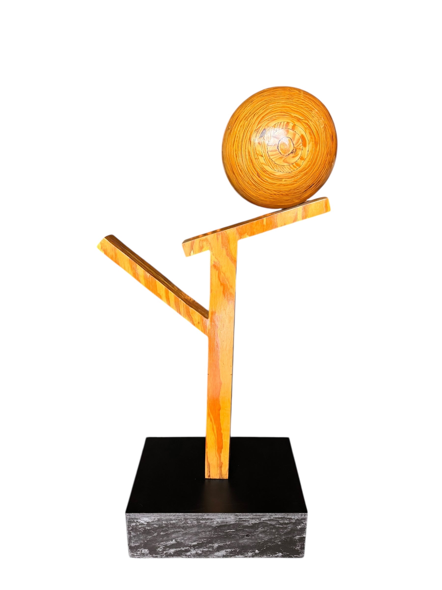 A wooden sculpture featuring a dark square base, a vertical trunk that branches into two angled supports, and a turned wooden sphere resting on the higher support.