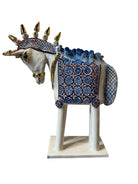 Ceramic horse by Domenico Pinto, featuring a white glazed body, geometric quilting on the saddle, a decorative crown with white and gold accents, and 24Kt gold detailing. The horse stands on four legs and is placed on a white base.