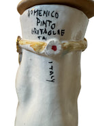 Handcrafted ceramic sculpture in the shape of a foot, decorated with intricate black and white patterns, 24KT gold accents, and topped with a blue lid featuring a gilt fish and head emerging from stylized waves.