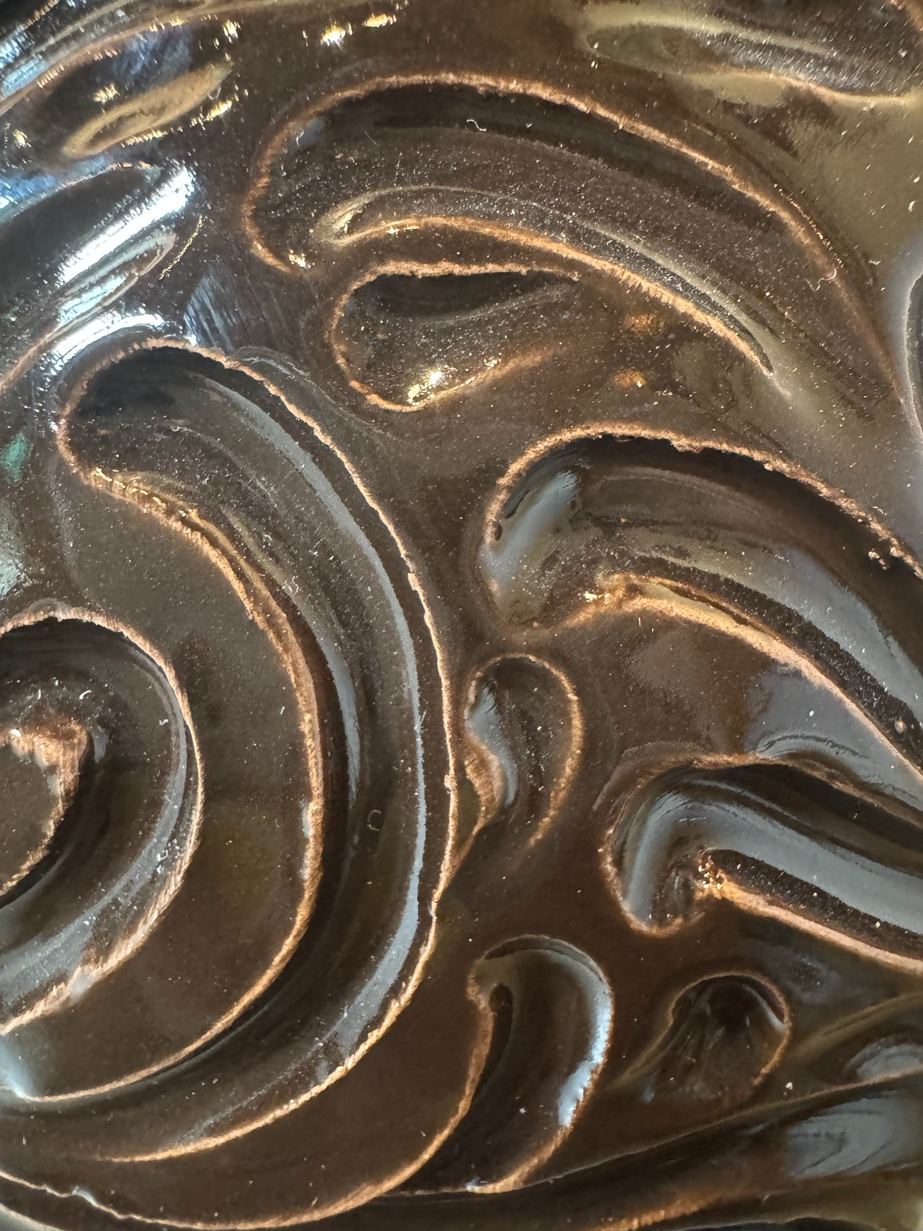 Glossy dark brown ceramic bull sculpture with intricate, hand-incised swirling patterns and a nose ring.