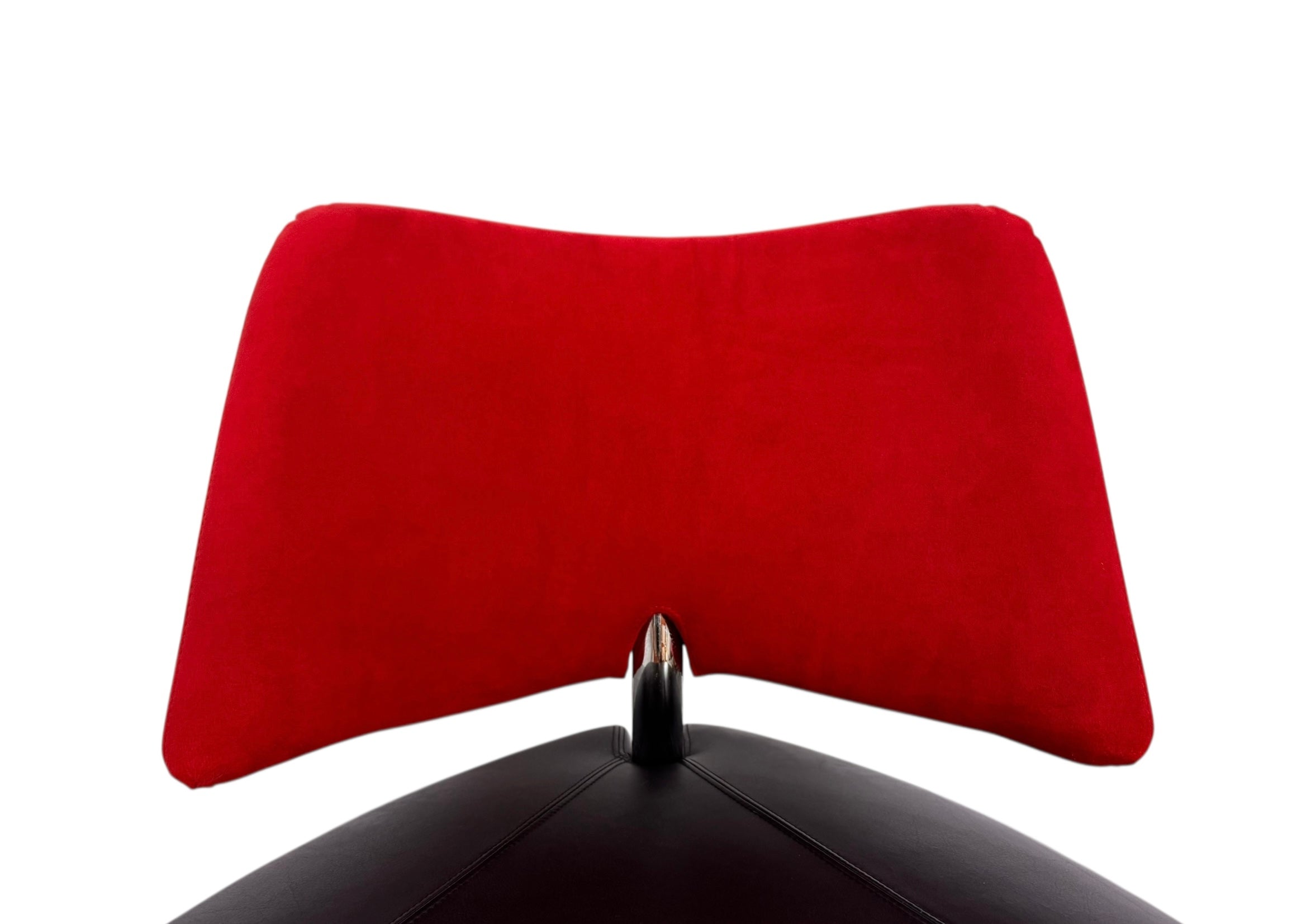 A Leolux Pallone armchair with a large, black, spherical leather seat and a smaller, red, curved leather backrest, supported by short metal legs.