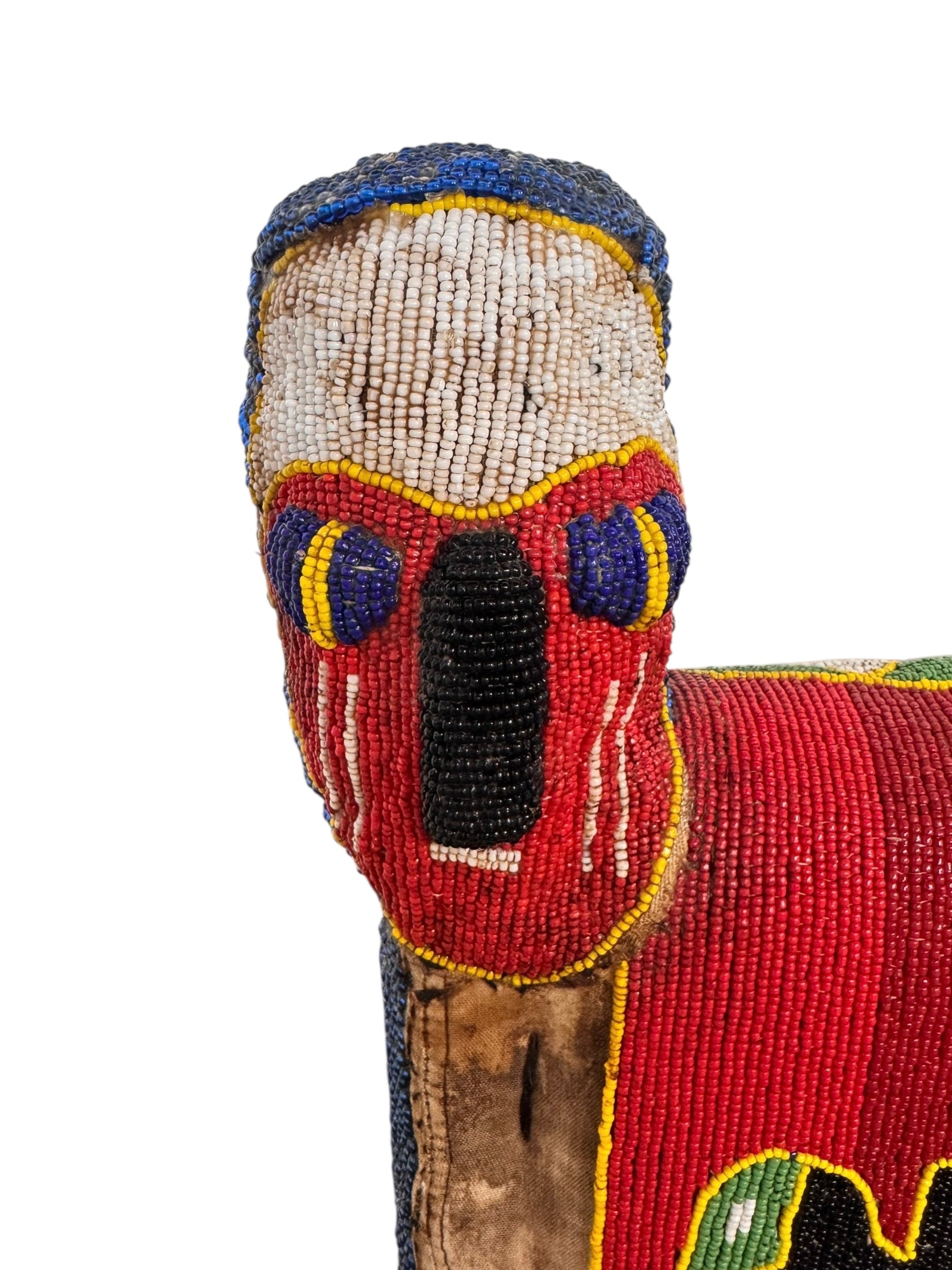 Close-up of a Yoruba beaded armchair, featuring vibrant red, blue, and green beads in a pattern of stylized masks and animals such as lions and zebras