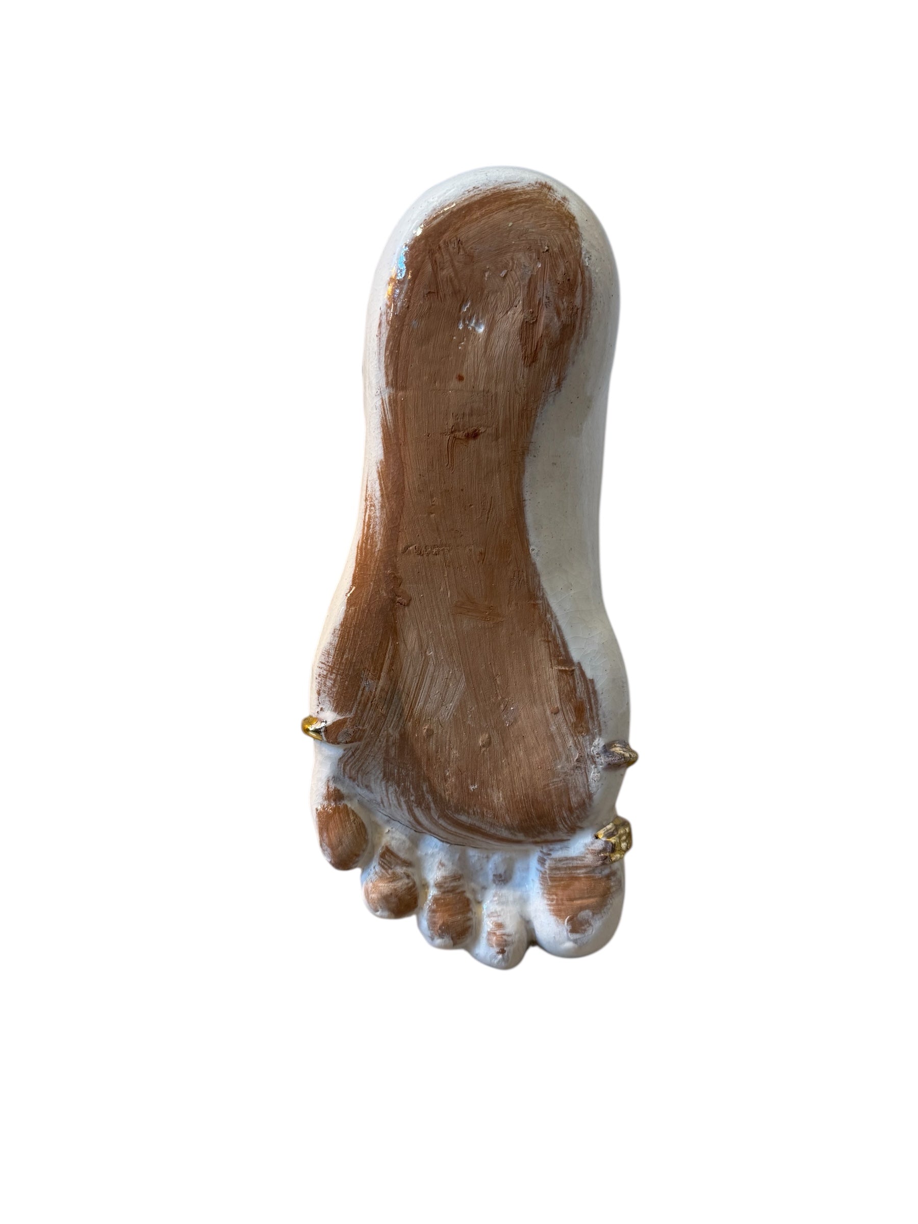 Close-up of a ceramic foot sculpture by Domenico Pinto. The foot is decorated with intricate hand-painted designs inspired by Apulian folklore and accented with 24KT gold. A stylized gilt mask sits atop the foot.