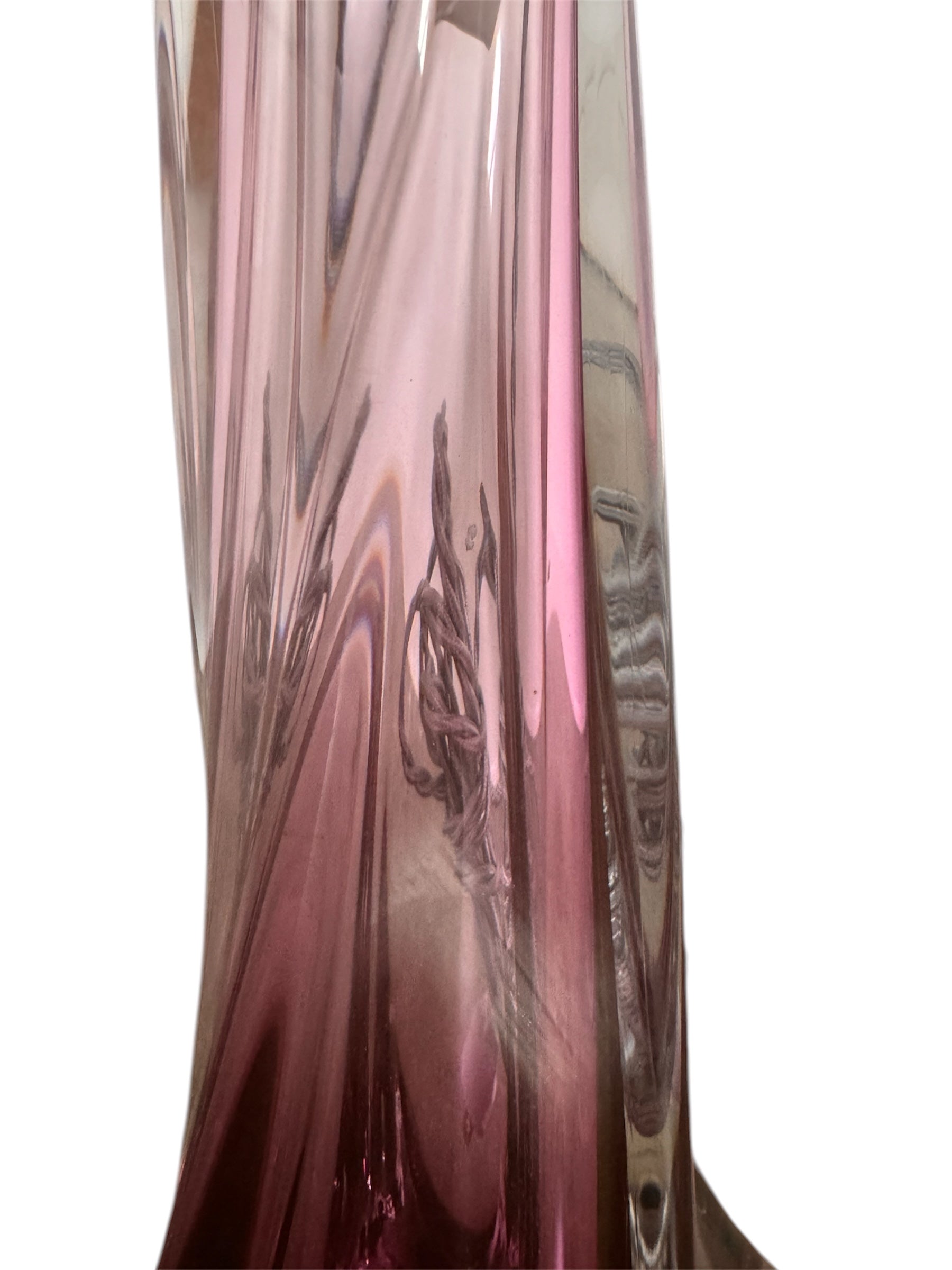 A tall, Mid-Century Modern sculptural table lamp featuring a hand-blown art glass base. The base is crafted in the Sommerso style, with a deep amethyst purple core encased in a thick, clear crystal outer layer that twists upward in an organic, fluid motion. The lamp is topped with a white, knife-pleated empire shade and a clear glass ball finial. The overall design is elegant and slender, emphasizing the contrast between the saturated purple glass and the transparent, light-refracting crystal.
