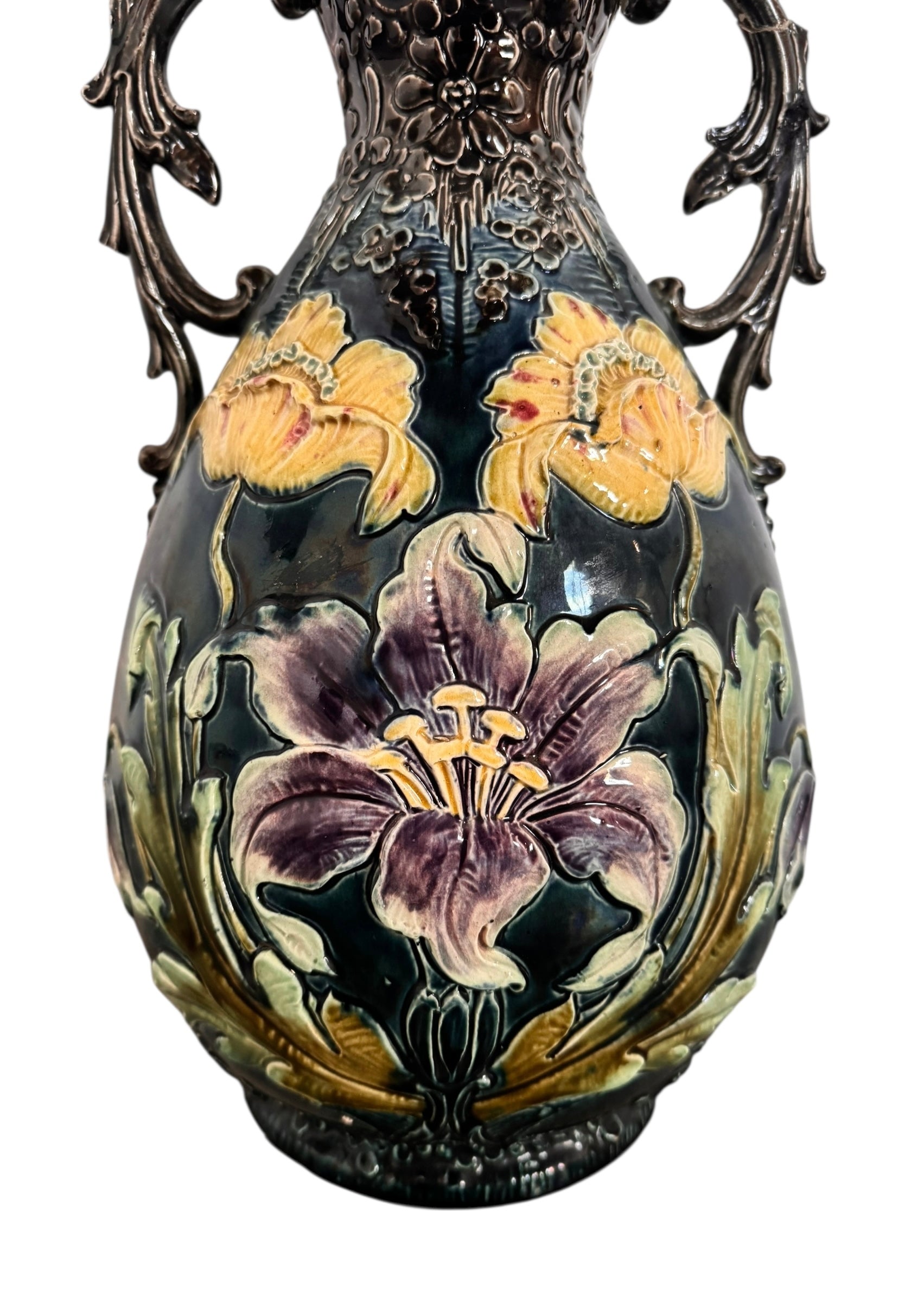 An ornate, dark glazed ceramic Art Nouveau vase with two handles and raised floral designs in yellow, purple, and green.