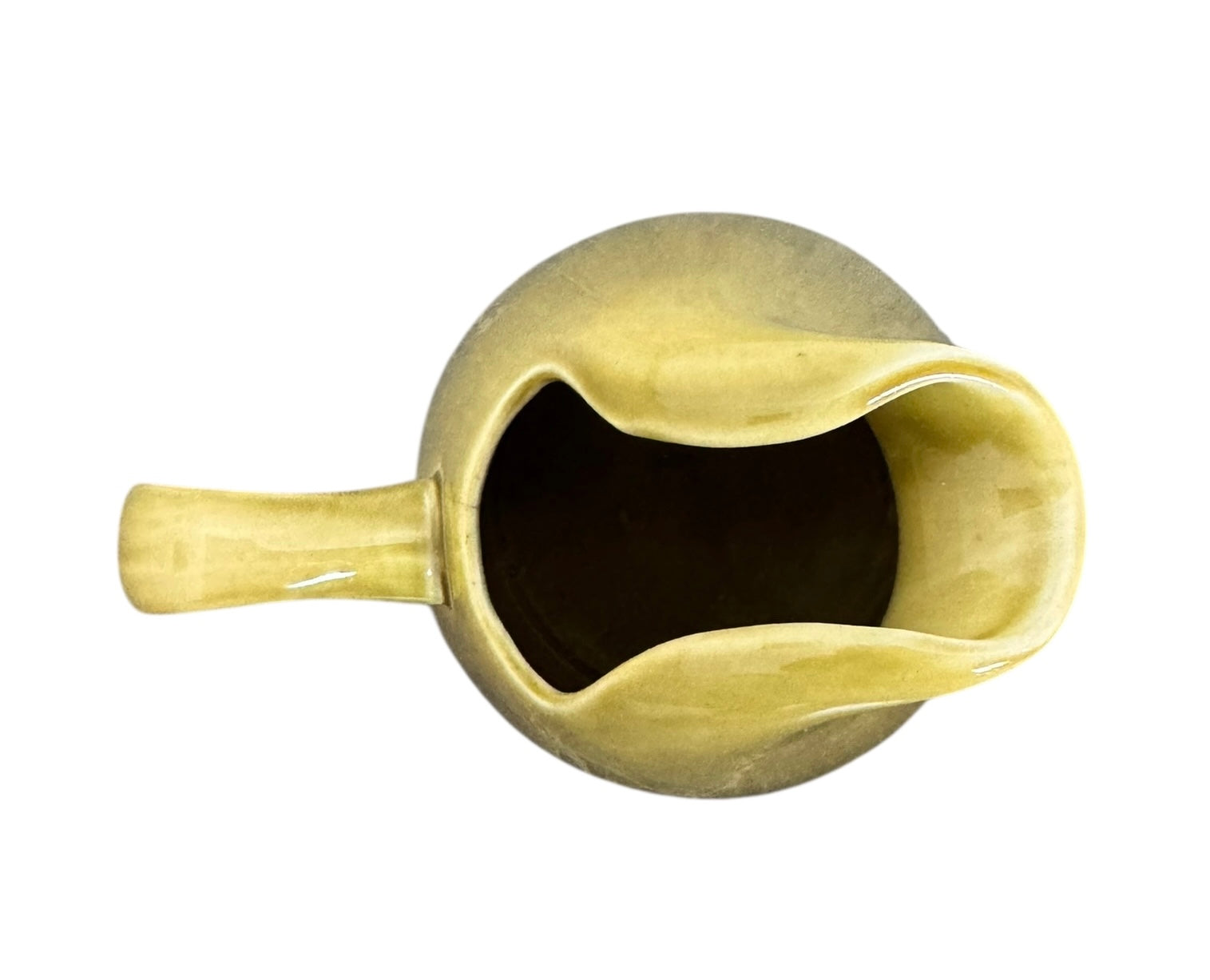 A chartreuse (yellow-green) ceramic pitcher designed by Russel Wright, featuring a teardrop shape, an elongated spout, and a curved handle