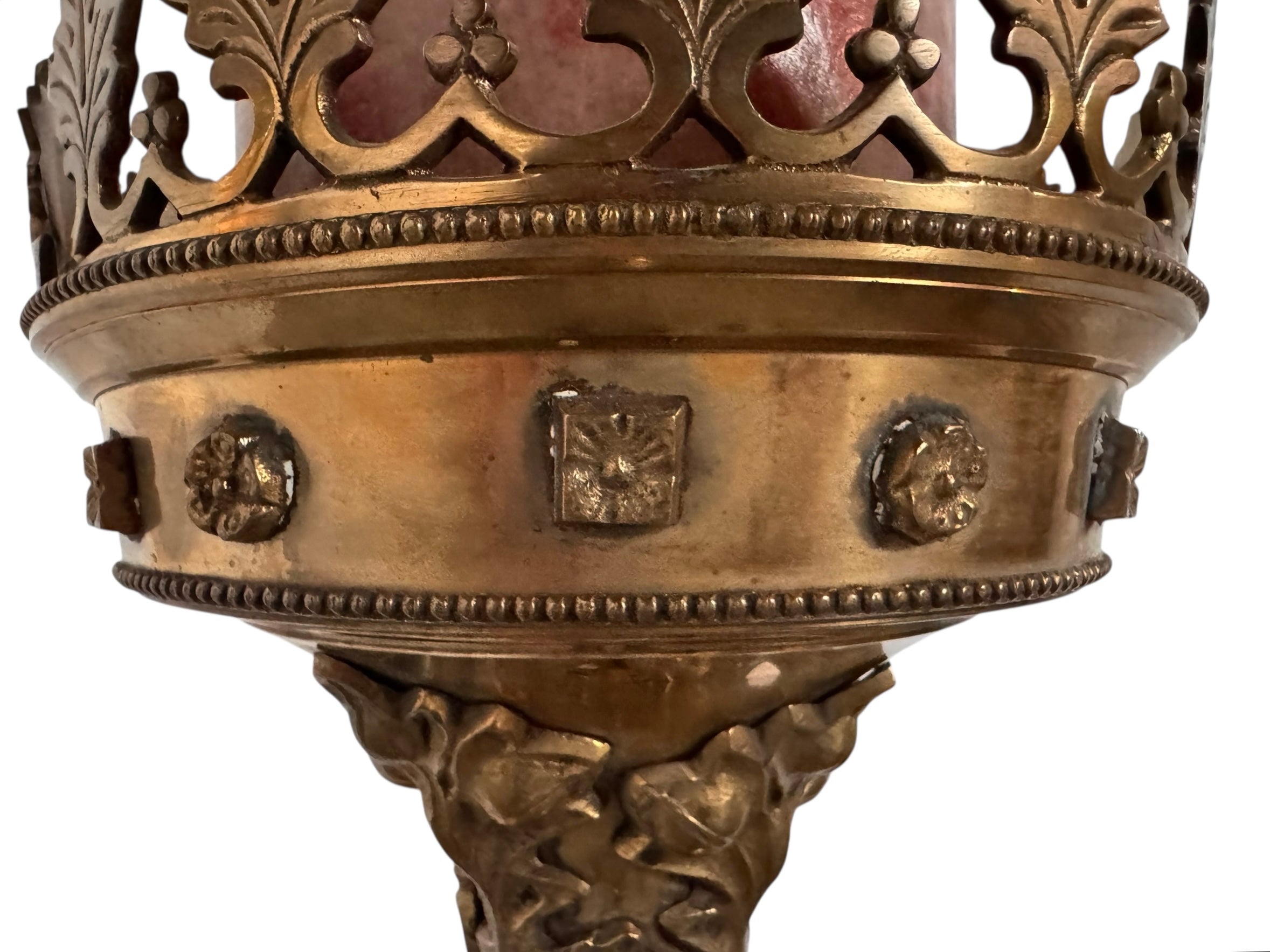 A tall, ornate, antique brass or bronze Gothic church candlestick holder with a pink candle in the top.