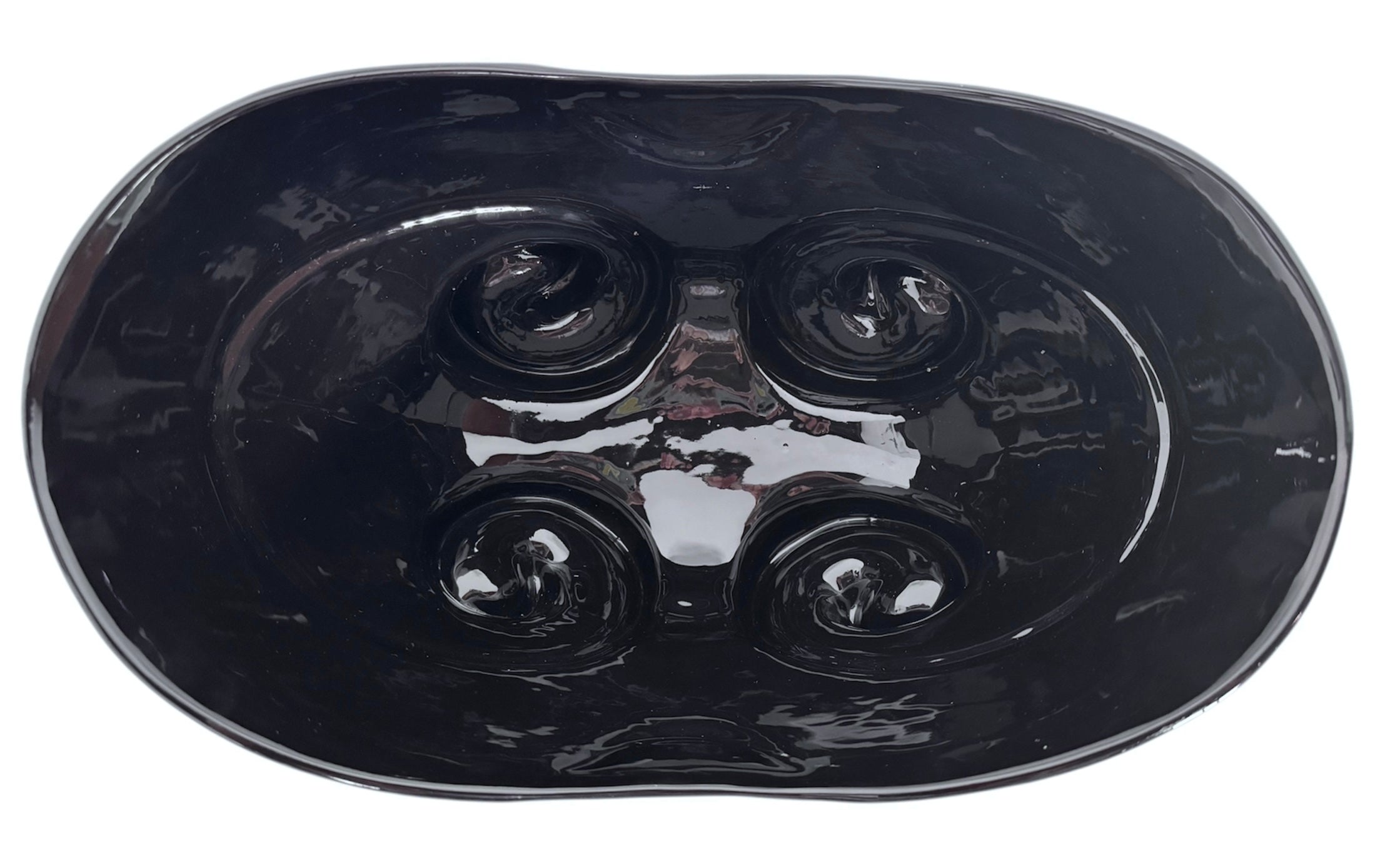 A large, decorative ceramic bowl by Dolbi Cashier in a dramatic Postmodern style. The top half is finished in a polished, piano-black glaze with an organic, wavy "butterfly" rim that dips in the center and rises at the sides. The bottom half is finished in a reflective, metallic silver chrome glaze, featuring bold, geometric-rounded feet and a structured base that appears to "hold" the black vessel. The overall shape is wide and sculptural, reminiscent of 1980s Art Deco Revival.