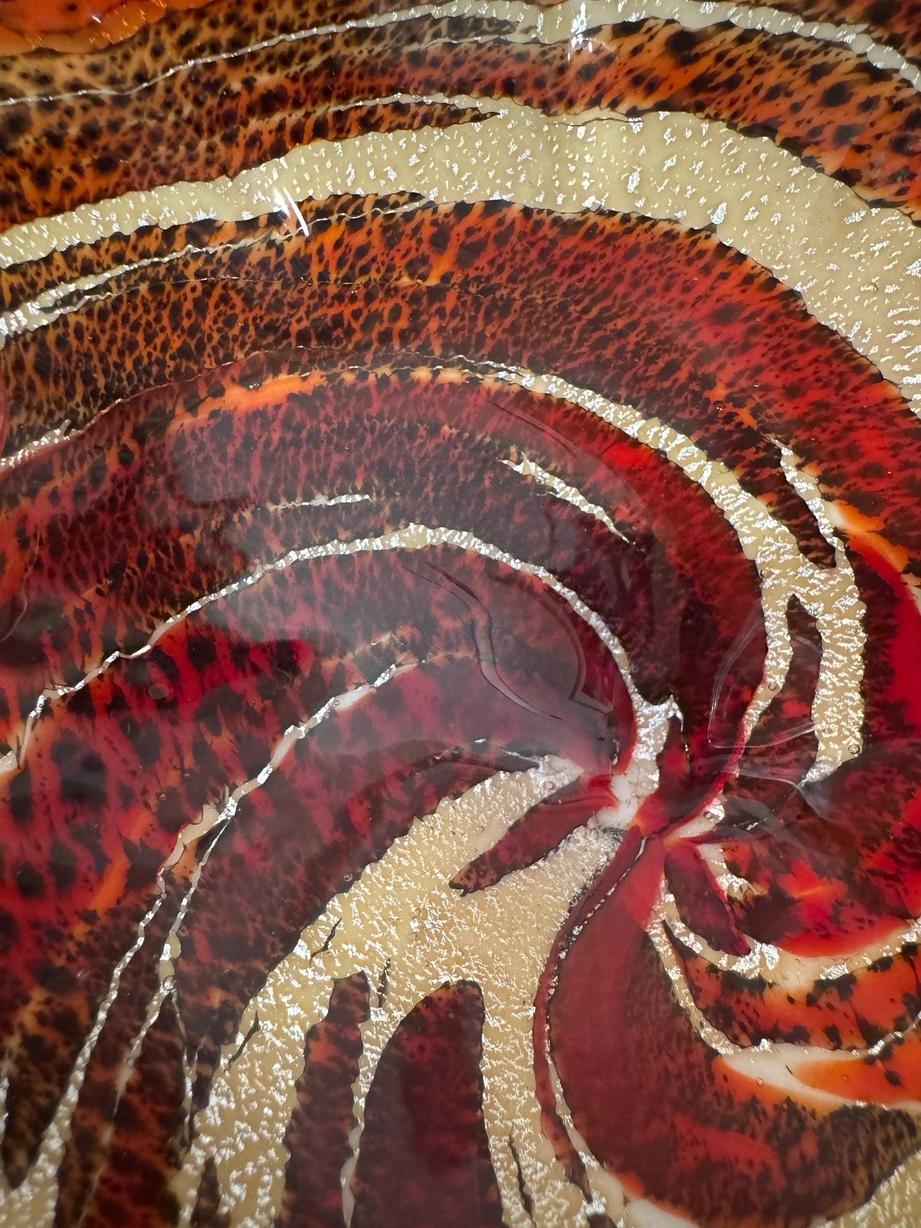 A Murano art glass bowl with a freeform shape, featuring layered swirls of brown, orange, and cream, accented with gold flecks. The bowl has a translucent white base.