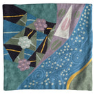 Decorative pillow with geometric patterns and floral elements on a teal background. Vibrant cross-stitched pillows from India with various artistic designs, sourced in Aix-en-Provence.