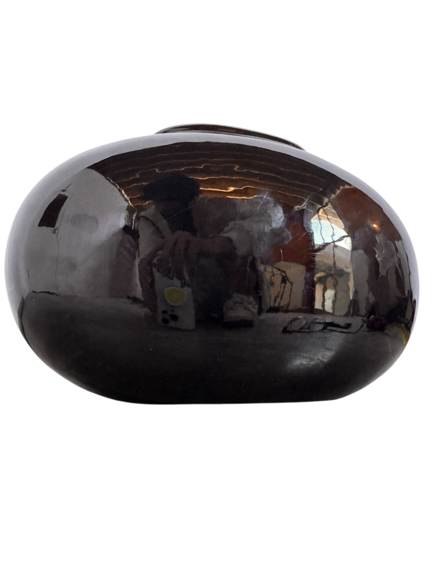 A round, glossy black vase with a small opening.
The vase has a spherical or gourd-like shape and a highly reflective, black glazed finish.