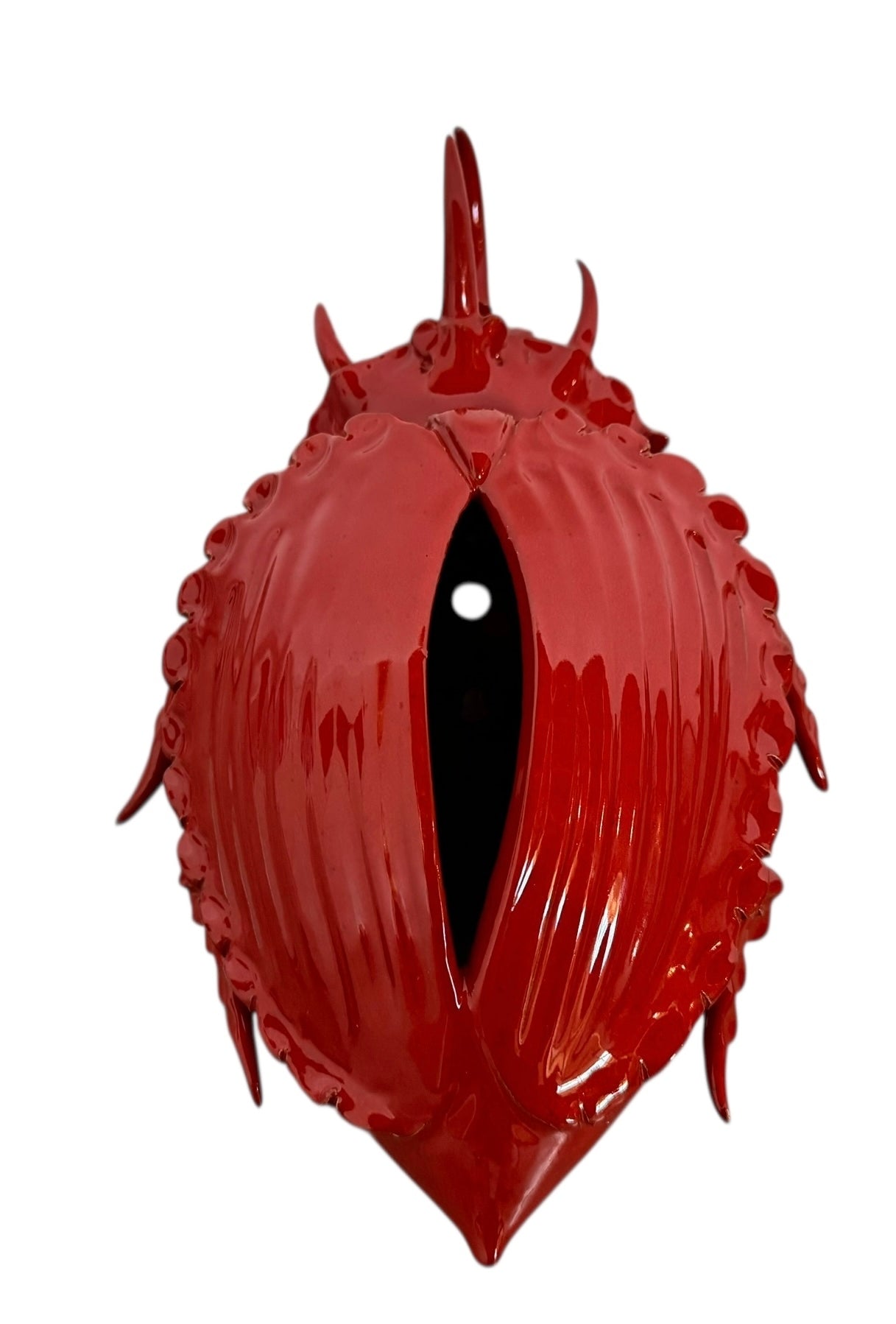 A vibrant, glossy red ceramic sculpture of a rhinoceros beetle by Enza Fasano. The piece features a highly reflective, deep crimson glaze that accentuates its smooth, rounded abdomen and the intricate, jagged textures of its head and horns.