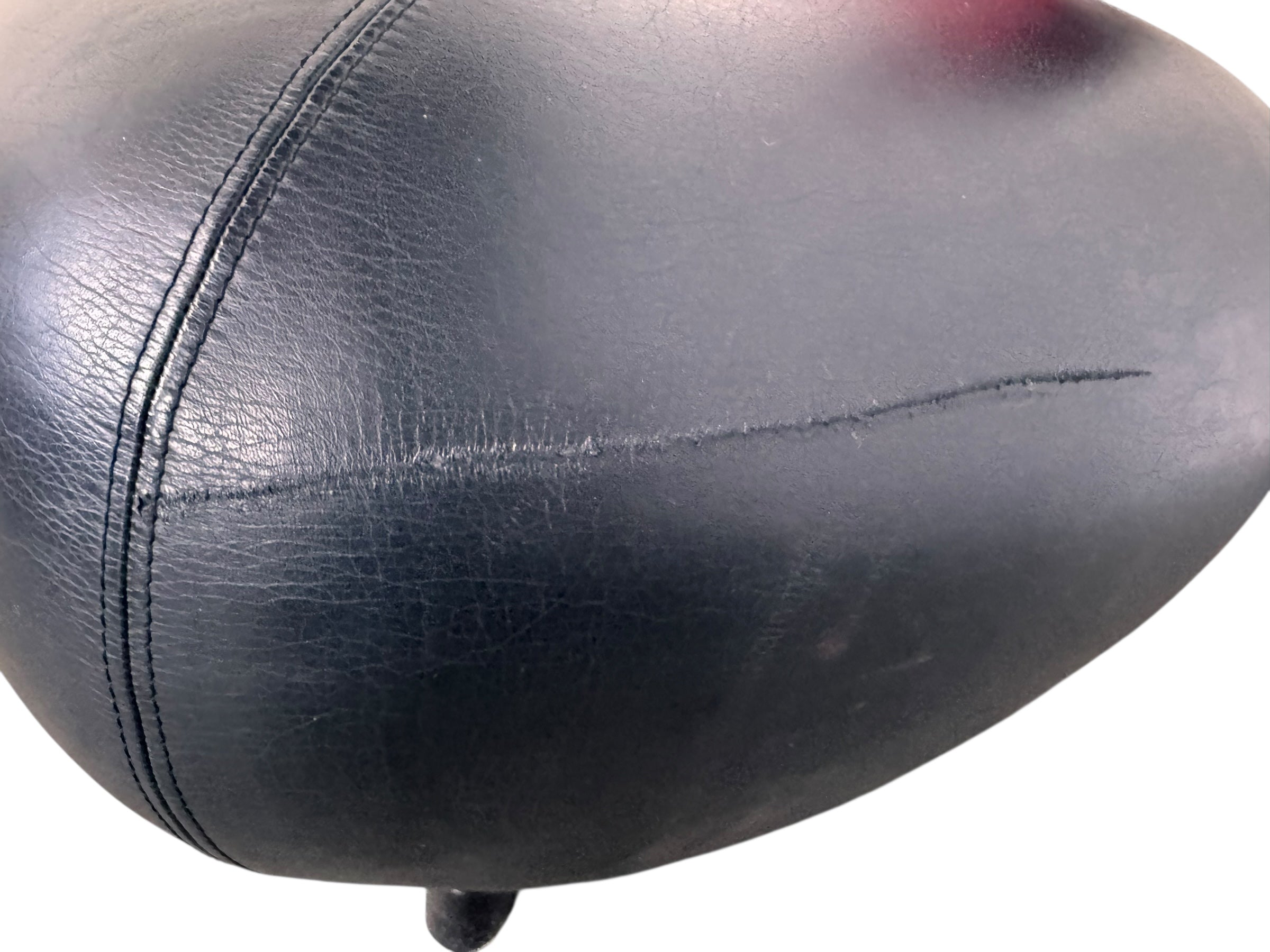 A Leolux Pallone armchair with a large, black, spherical leather seat and a smaller, red, curved leather backrest, supported by short metal legs.