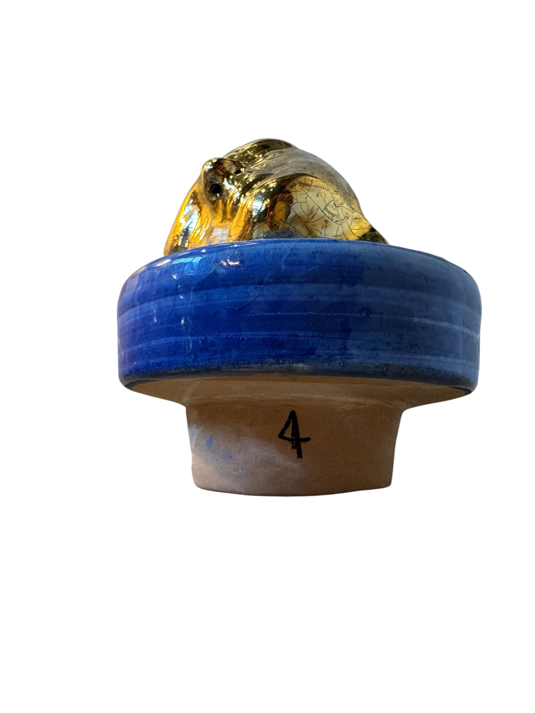 Close-up of a ceramic foot sculpture by Domenico Pinto. The foot is decorated with intricate hand-painted designs inspired by Apulian folklore and accented with 24KT gold. A stylized gilt mask sits atop the foot.