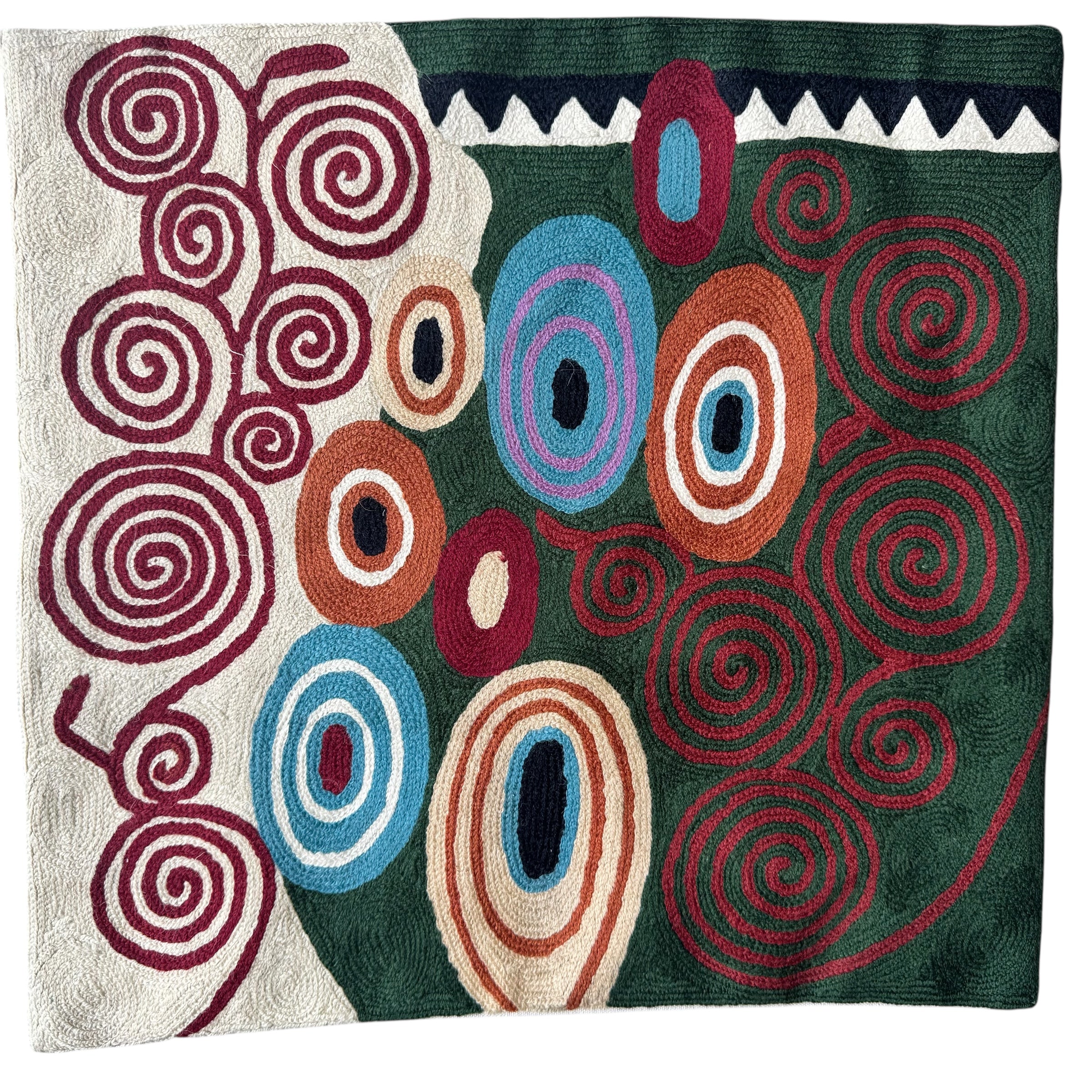 Colorful abstract patterned pillow.with swirling designs on a plain background. Vibrant cross-stitched pillows from India with various artistic designs, sourced in Aix-en-Provence.