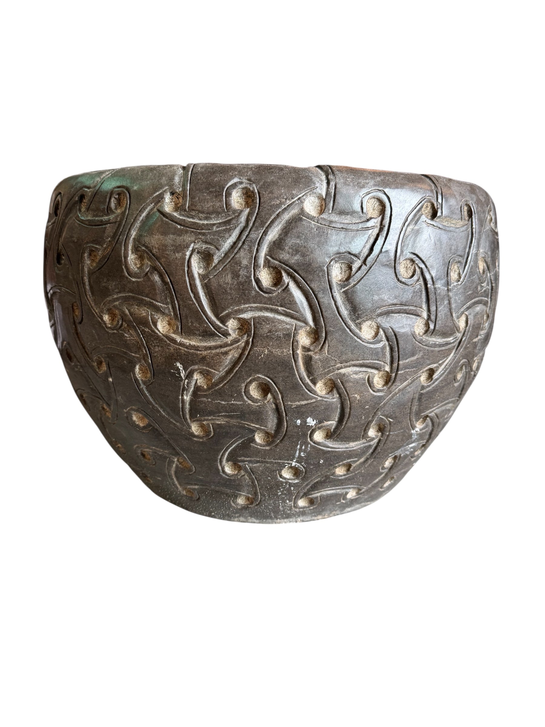 A heavy stone planter, featuring an intricate, hand-carved pattern resembling Celtic knot work.