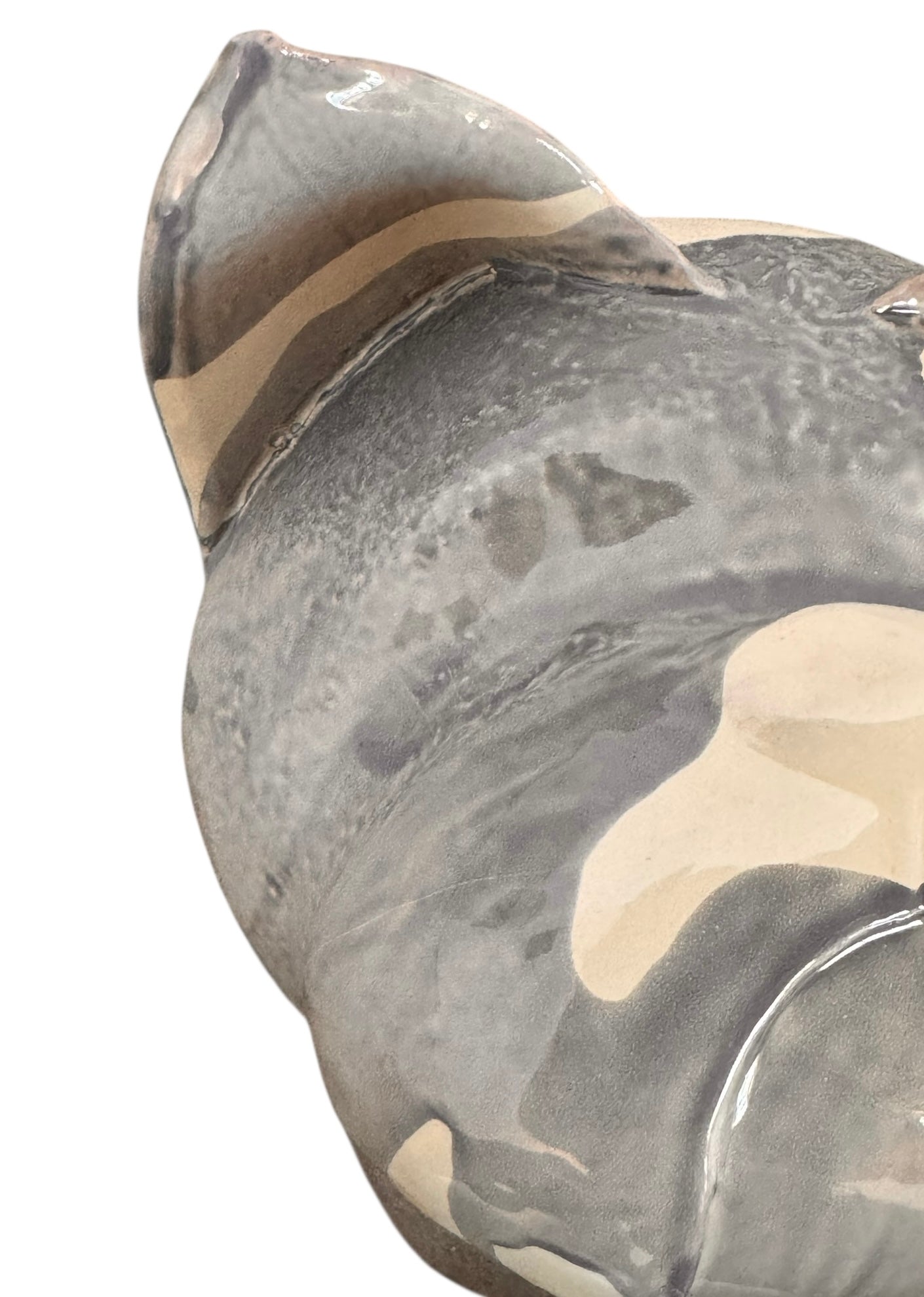 A ceramic sculpture of a bulldog's head by Enza Fasano. The piece features a glossy, glazed finish with a sophisticated color palette of muted greys, creams, and earthy brown tones arranged in bold, abstract striped patterns across the face and ears. The bulldog has characteristic folded ears, a prominent snout, and a soulful, slightly downturned expression. The sculpture is set against a clean, white background, highlighting its smooth texture and reflective surface.