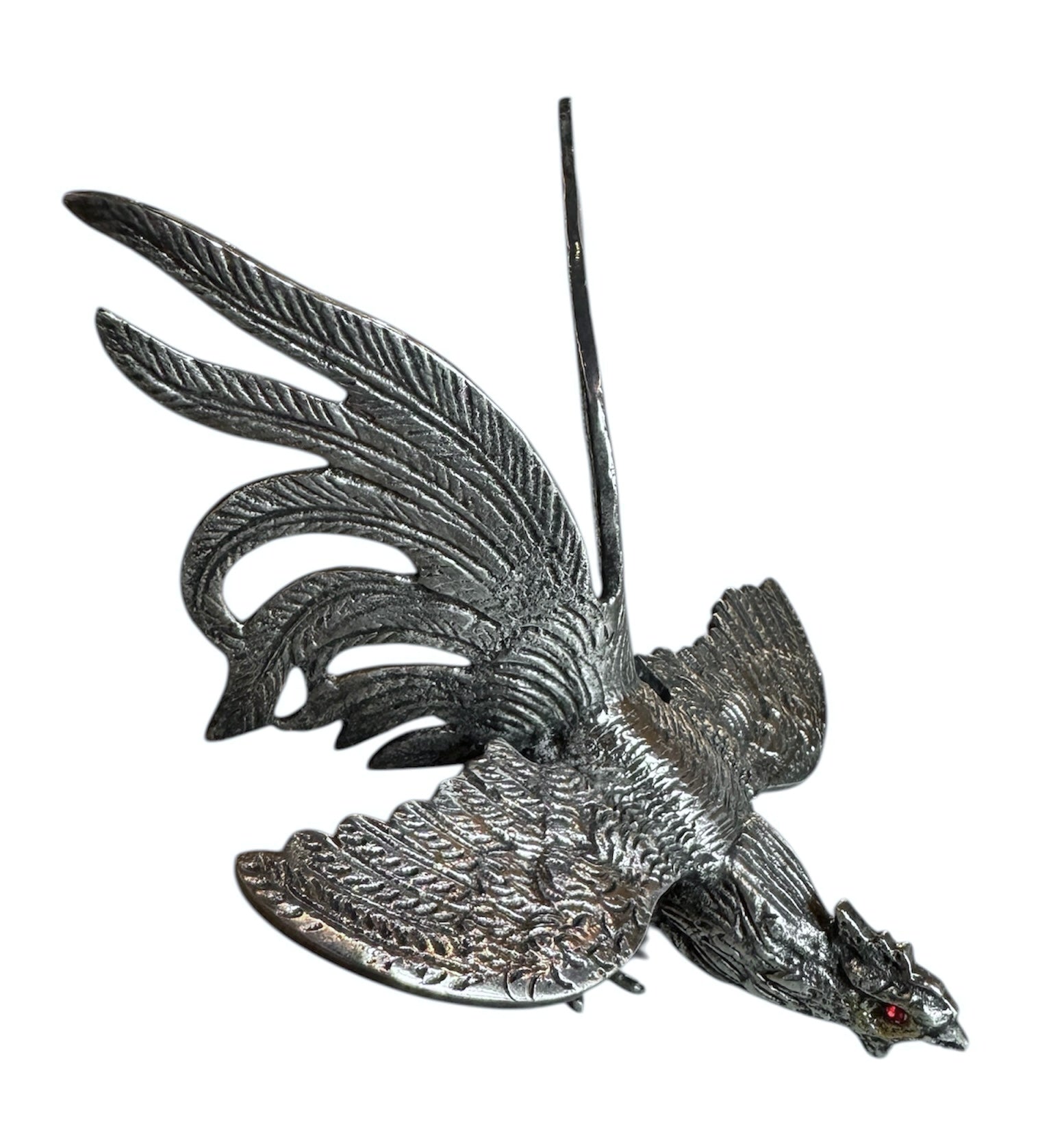 A pair of vintage, silver-plated brass fighting rooster figurines positioned in a confrontational stance against a white background. The rooster on the left is crouched low with its head down and tail feathers fanned high, while the rooster on the right stands more upright with its wings slightly flared. Both feature intricate feather detailing, a metallic patina showing hints of brass through the silver, and small, bright red glass eyes.
