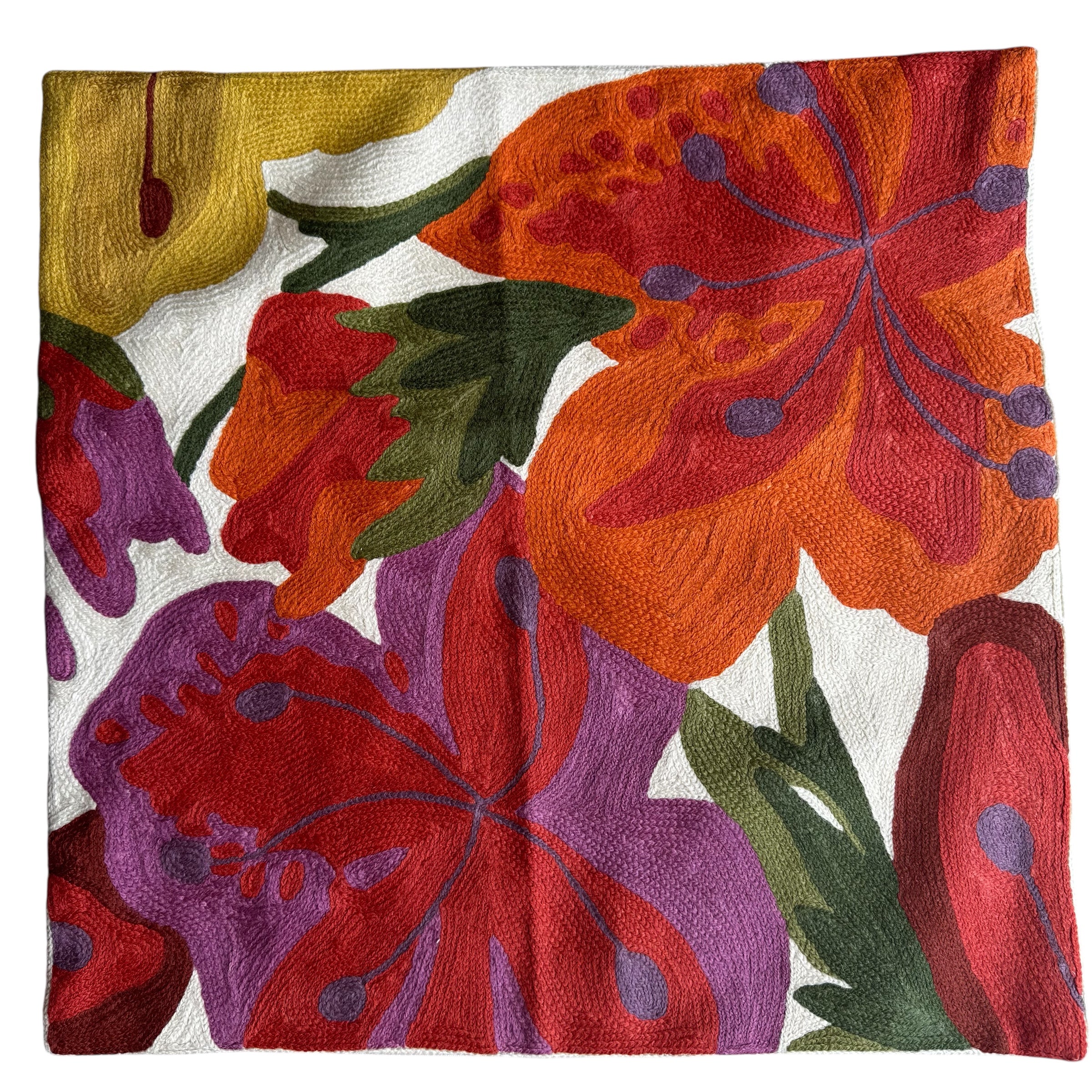 Orange. Purple. yellow flower motif . White background.Vibrant cross-stitched pillows from India with various artistic designs, sourced in Aix-en-Provence.