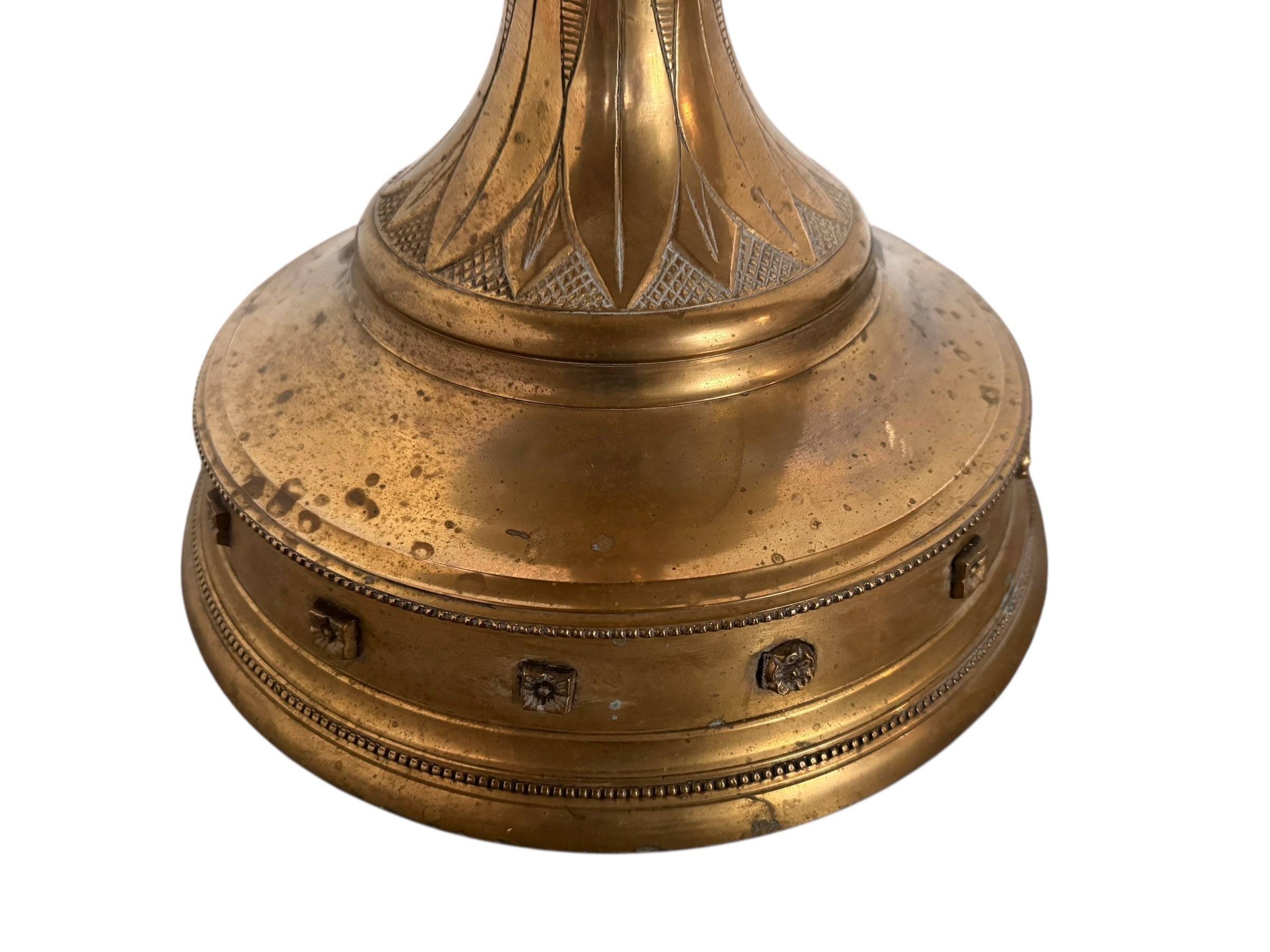 A tall, ornate, antique brass or bronze Gothic church candlestick holder with a pink candle in the top.