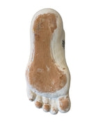 Handcrafted ceramic sculpture in the shape of a foot, decorated with intricate black and white patterns, 24KT gold accents, and topped with a blue lid featuring a gilt fish and head emerging from stylized waves.