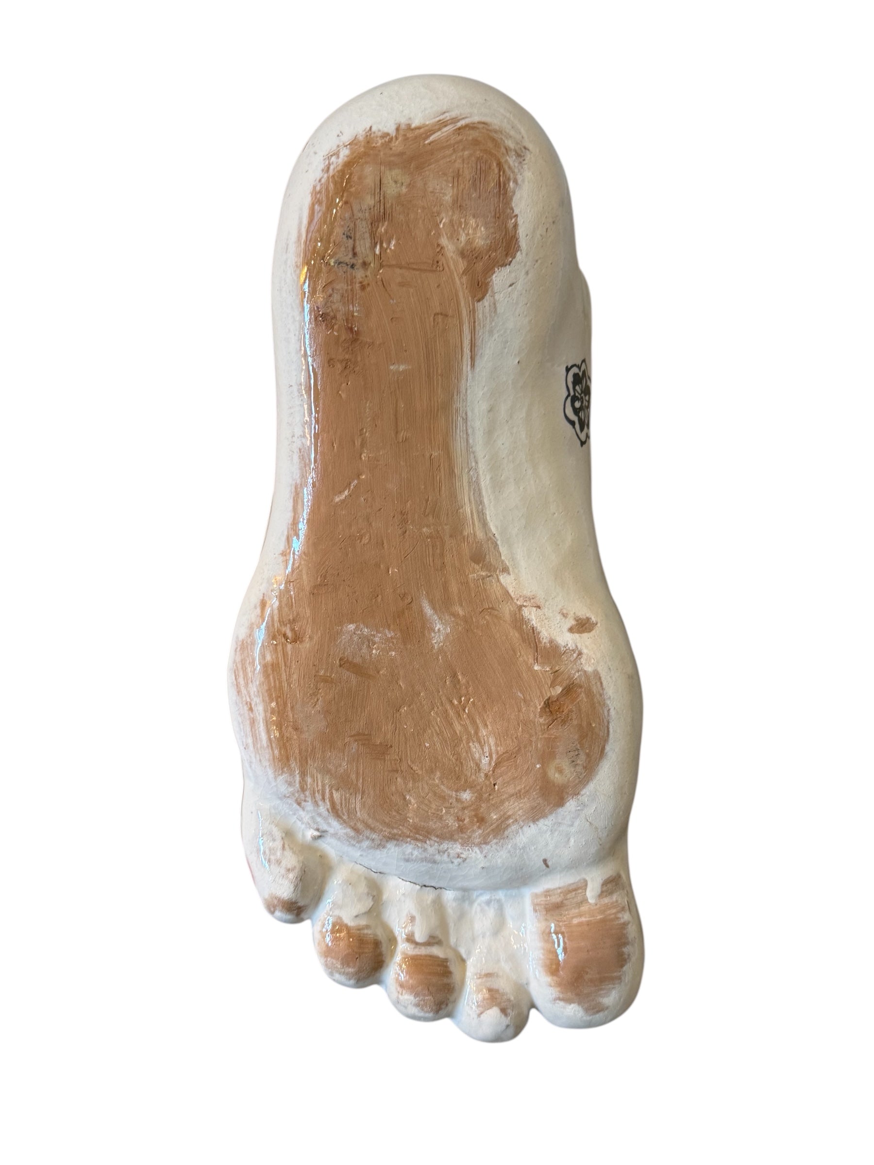 Handcrafted ceramic sculpture in the shape of a foot, decorated with intricate black and white patterns, 24KT gold accents, and topped with a blue lid featuring a gilt fish and head emerging from stylized waves.