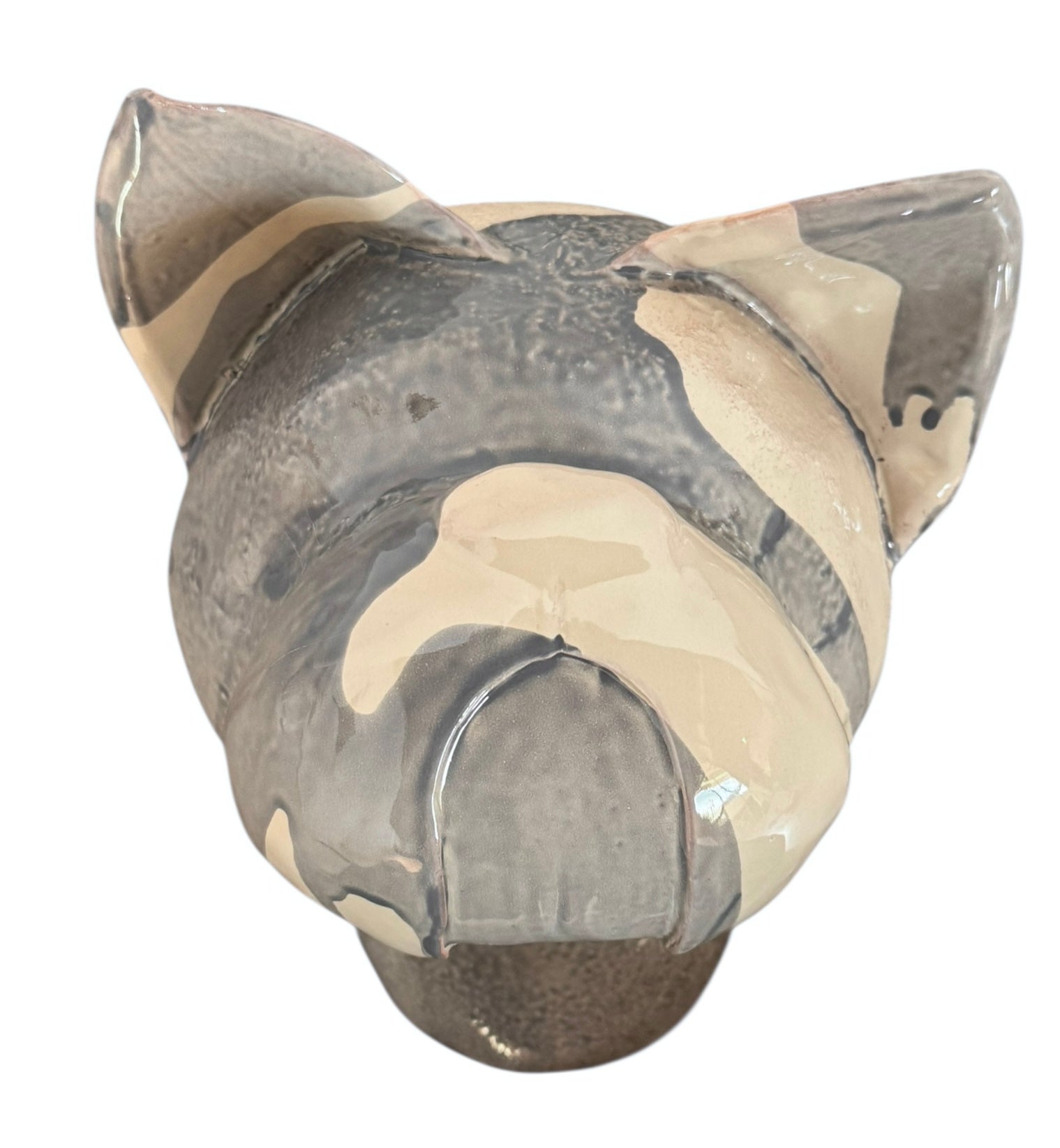 A ceramic sculpture of a bulldog's head by Enza Fasano. The piece features a glossy, glazed finish with a sophisticated color palette of muted greys, creams, and earthy brown tones arranged in bold, abstract striped patterns across the face and ears. The bulldog has characteristic folded ears, a prominent snout, and a soulful, slightly downturned expression. The sculpture is set against a clean, white background, highlighting its smooth texture and reflective surface.