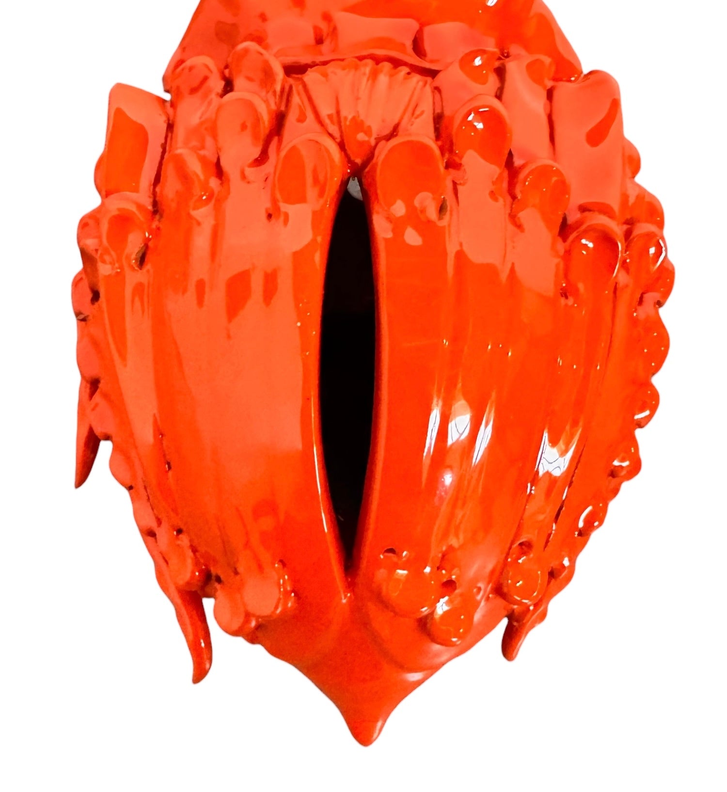 A glossy, vibrant orange ceramic sculpture of a rhinoceros beetle by Enza Fasano. The piece features a highly polished, reflective glaze and stylized, fluid anatomical details. Its prominent dual horns curve forward, and the body is textured with layered, wing-like plates, set against a plain white background.