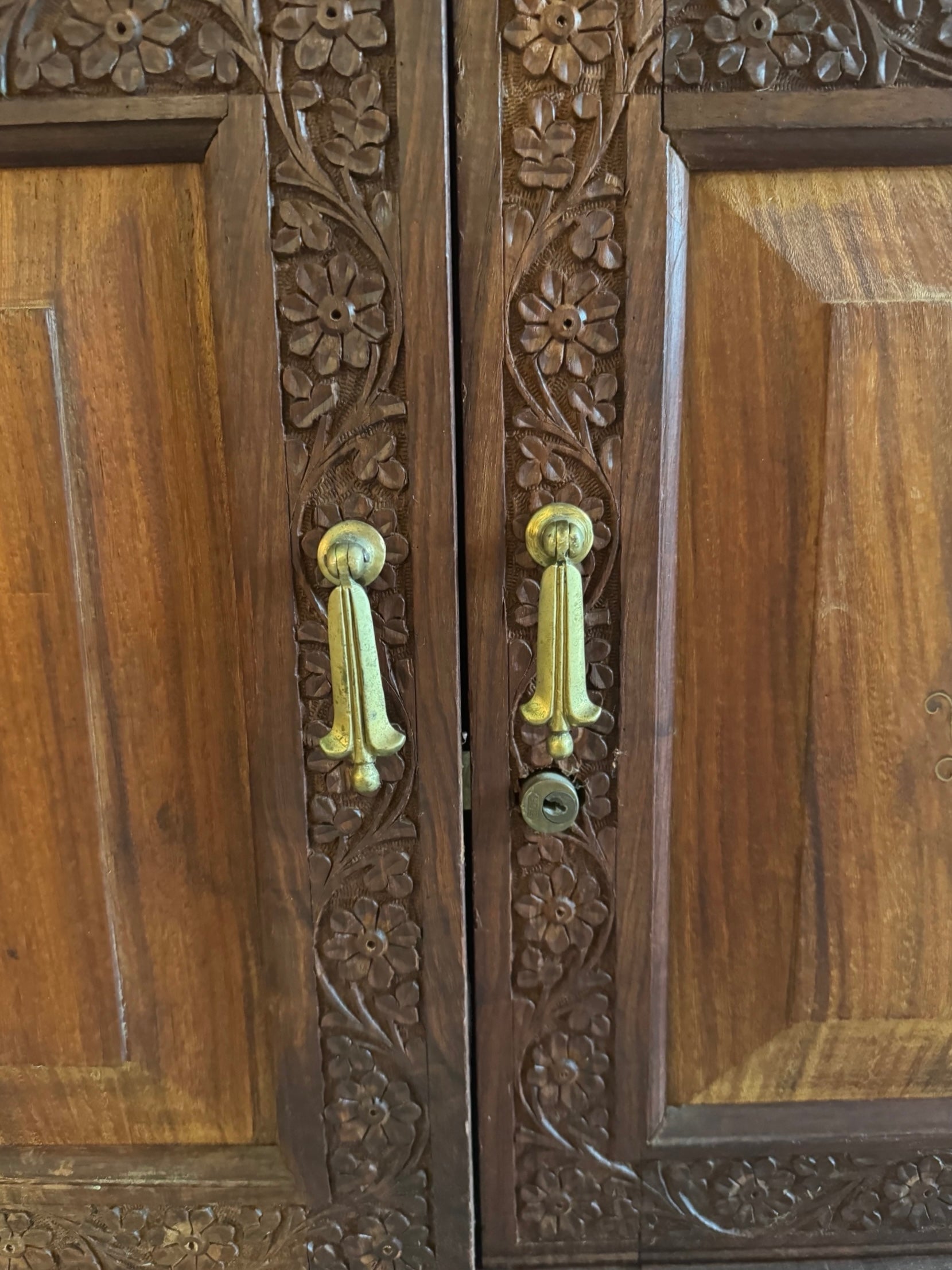Antique bar cabinet with wood inlay and brass floral details, open to reveal interior shelving and bar storage