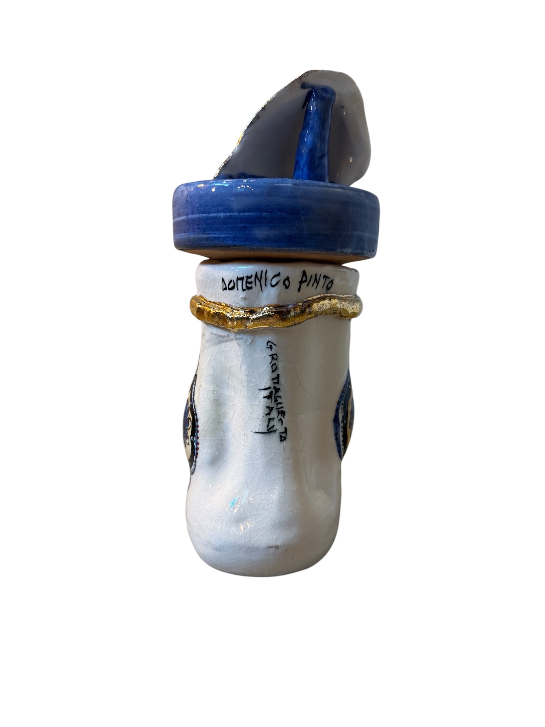 Close-up of a ceramic foot sculpture by Domenico Pinto. The foot is decorated with intricate hand-painted designs inspired by Apulian folklore and accented with 24KT gold. A stylized gilt mask sits atop the foot.