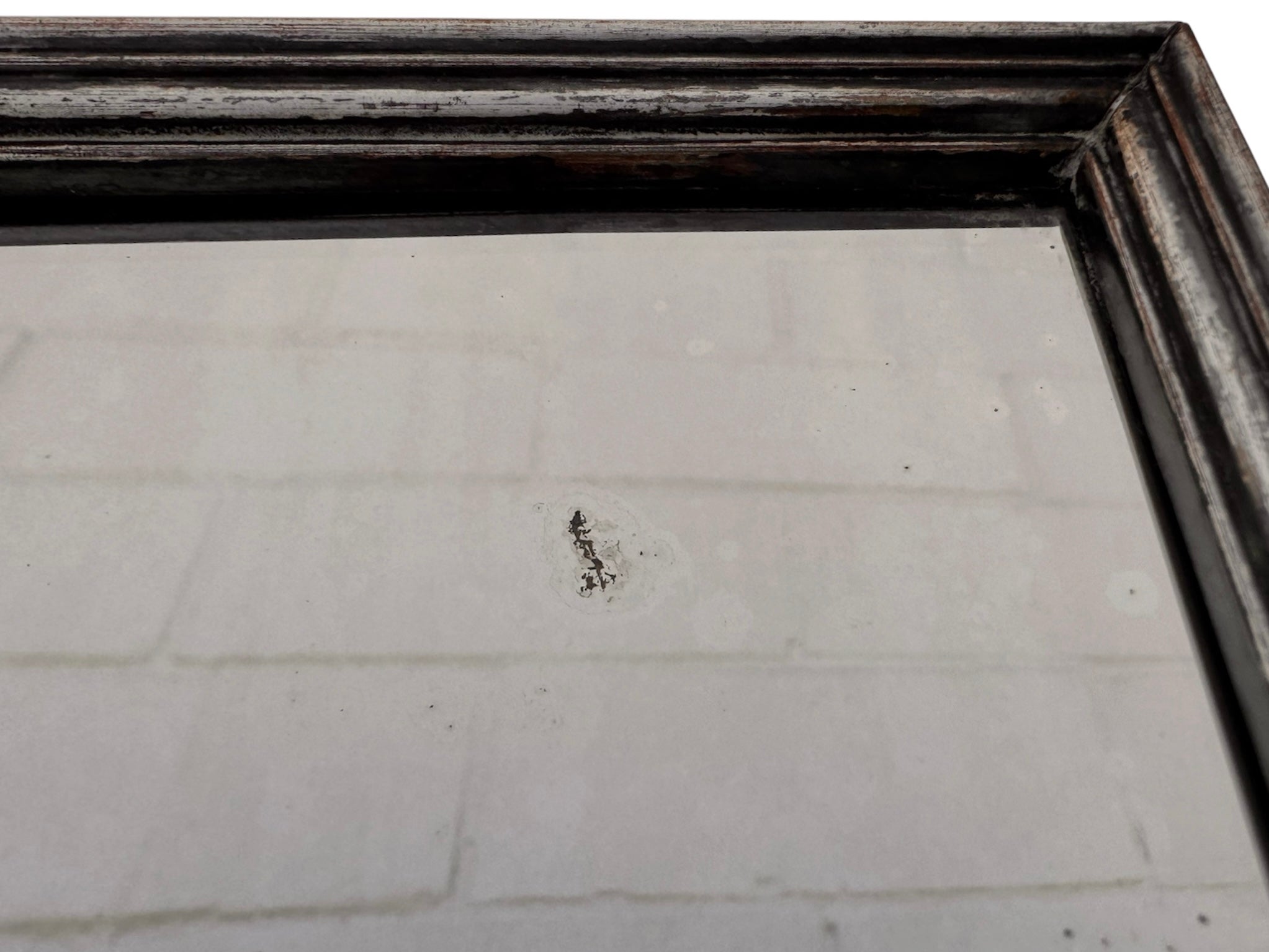 The antique Chevalier Mirror features a rectangular swing frame supported by two turned posts on decorative trestle feet. The mirror stands on four scrolled feet and features its original tarnished, silvered finish. The front of the mirror reflects a bright blue sky with wispy white clouds. The original dark brown backing is still attached to the frame.