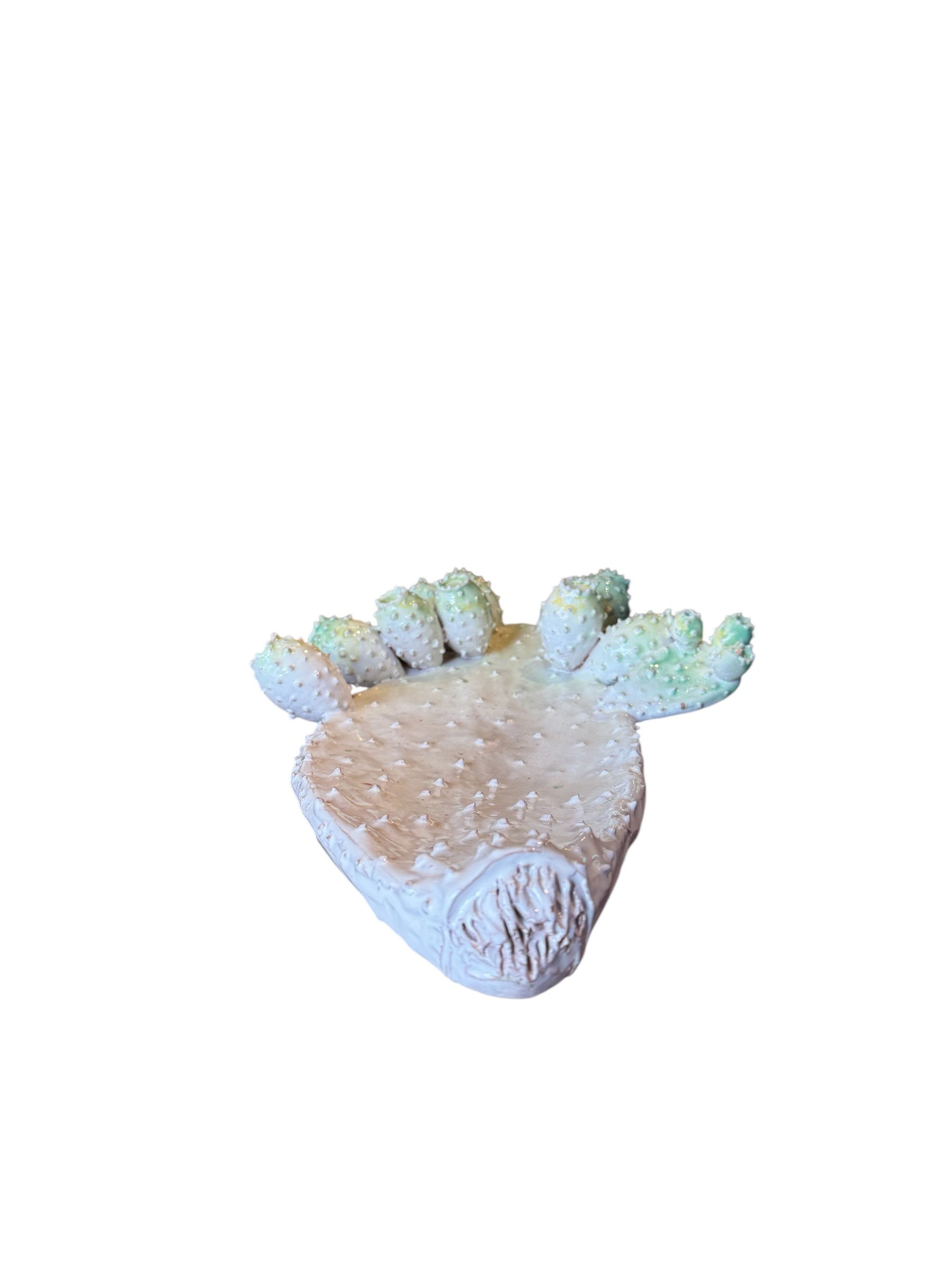 A white and green, glazed ceramic platter in the shape of a prickly pear cactus pad with attached prickly pear fruit. The surface has raised dots representing spines.