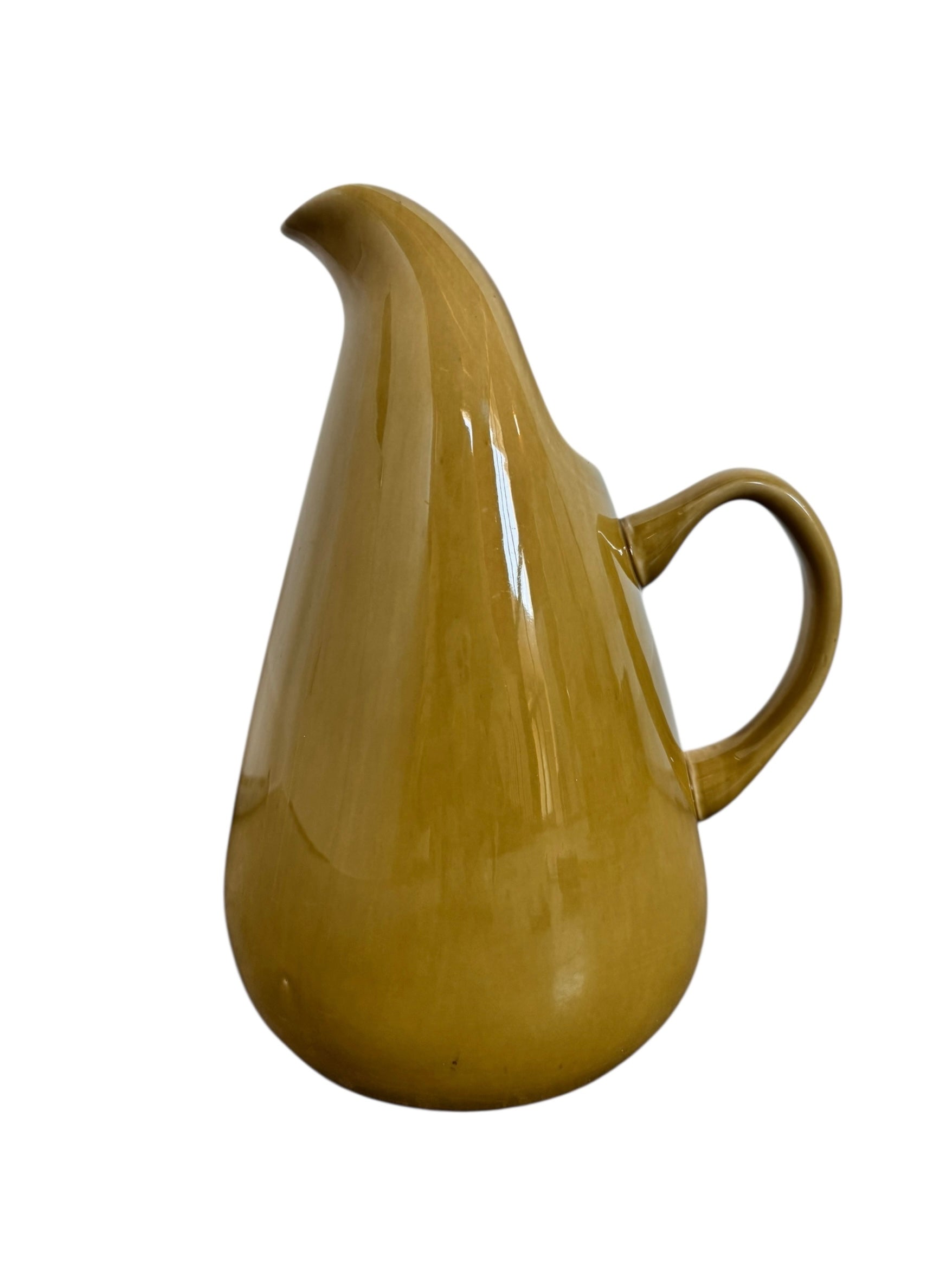 A chartreuse (yellow-green) ceramic pitcher designed by Russel Wright, featuring a teardrop shape, an elongated spout, and a curved handle