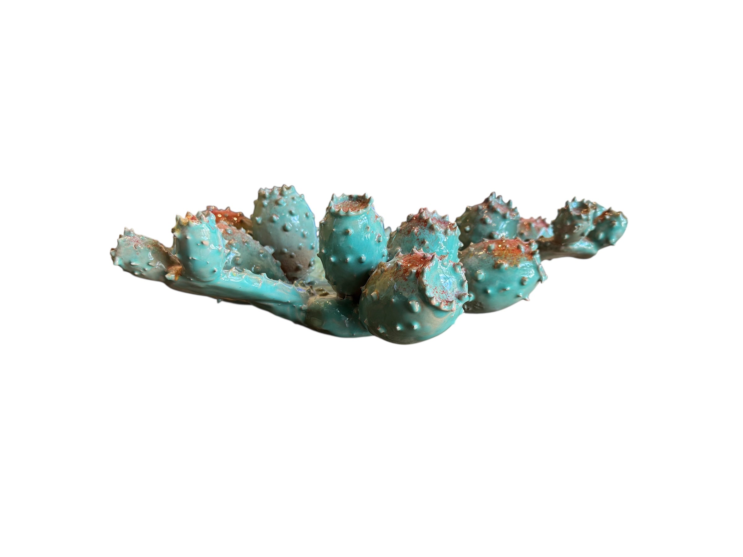 A green and red, glazed ceramic platter in the shape of a prickly pear cactus pad with attached prickly pear fruit. The surface has raised dots representing spines.