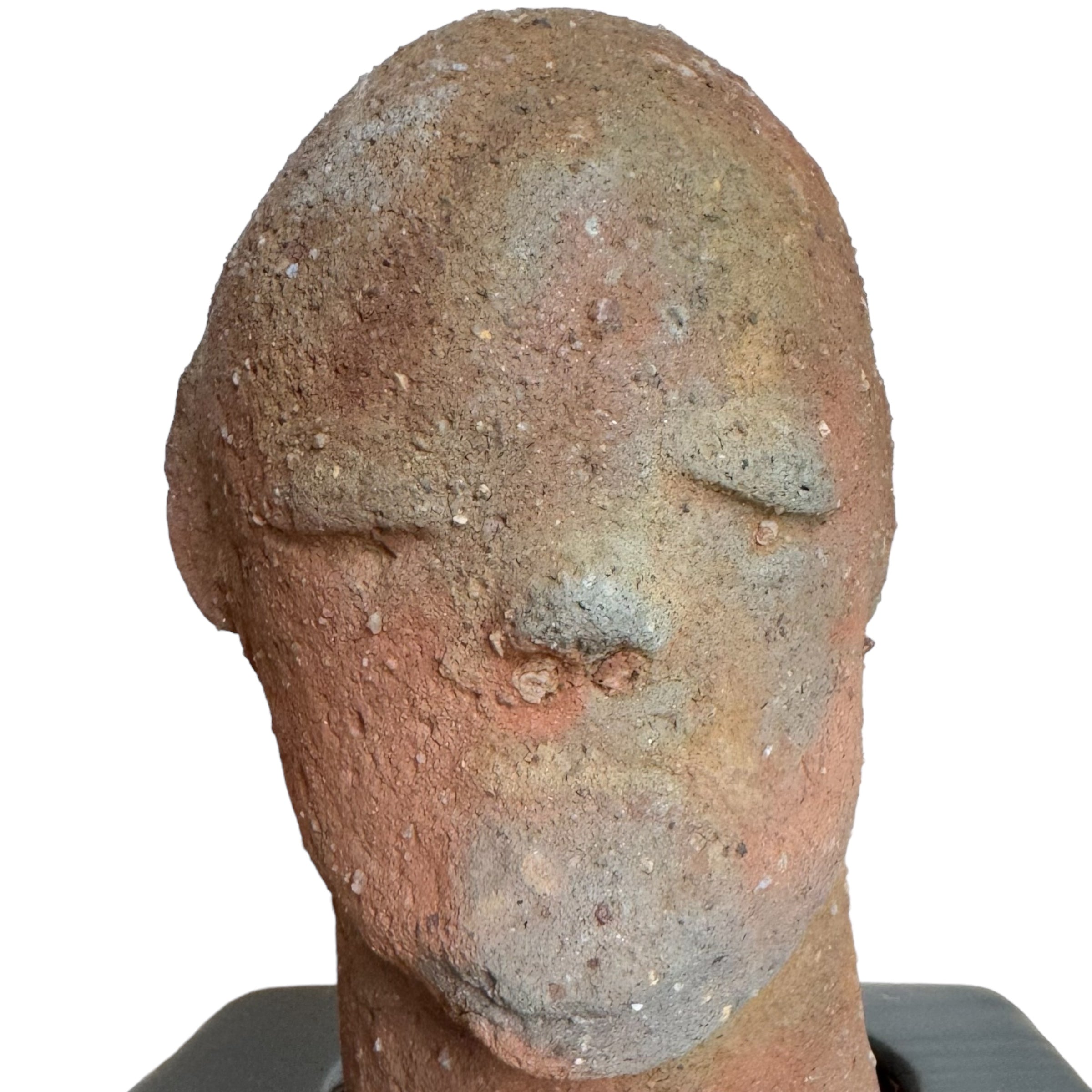 An ancient African terracotta sculpture of a head with closed eyes and a bearded face, mounted on a custom wood base.