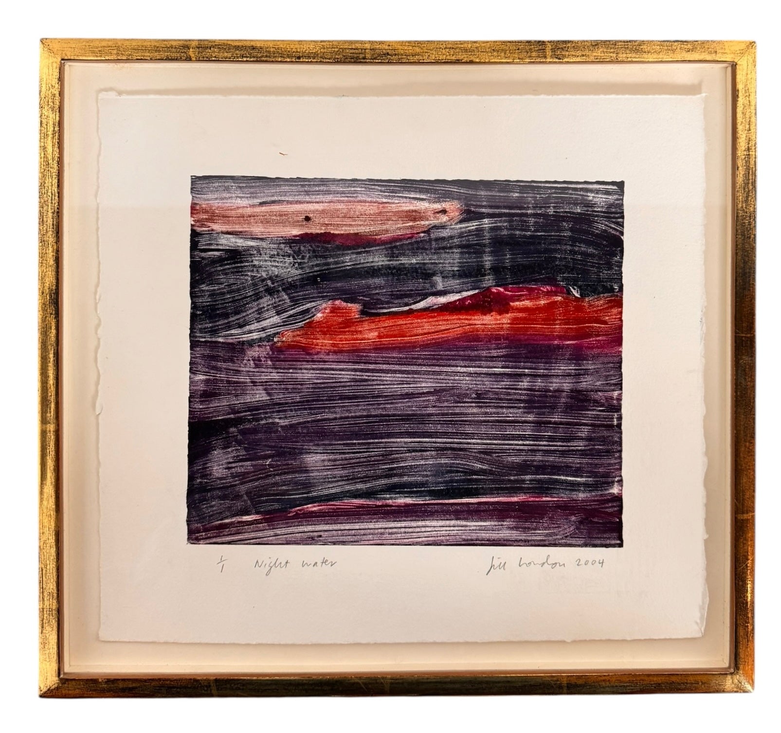 A horizontal, rectangular abstract print titled "Night Water" centered within a white mat and a thin gold frame. The artwork features dense, textured horizontal brushstrokes in deep shades of violet, indigo, and black. A prominent, gestural streak of vibrant red and a softer blush-pink band cut across the dark "water," suggesting a sunset reflection or light hitting a dark surface. The artist's signature, title, and the year 2004 are visible in pencil at the bottom.